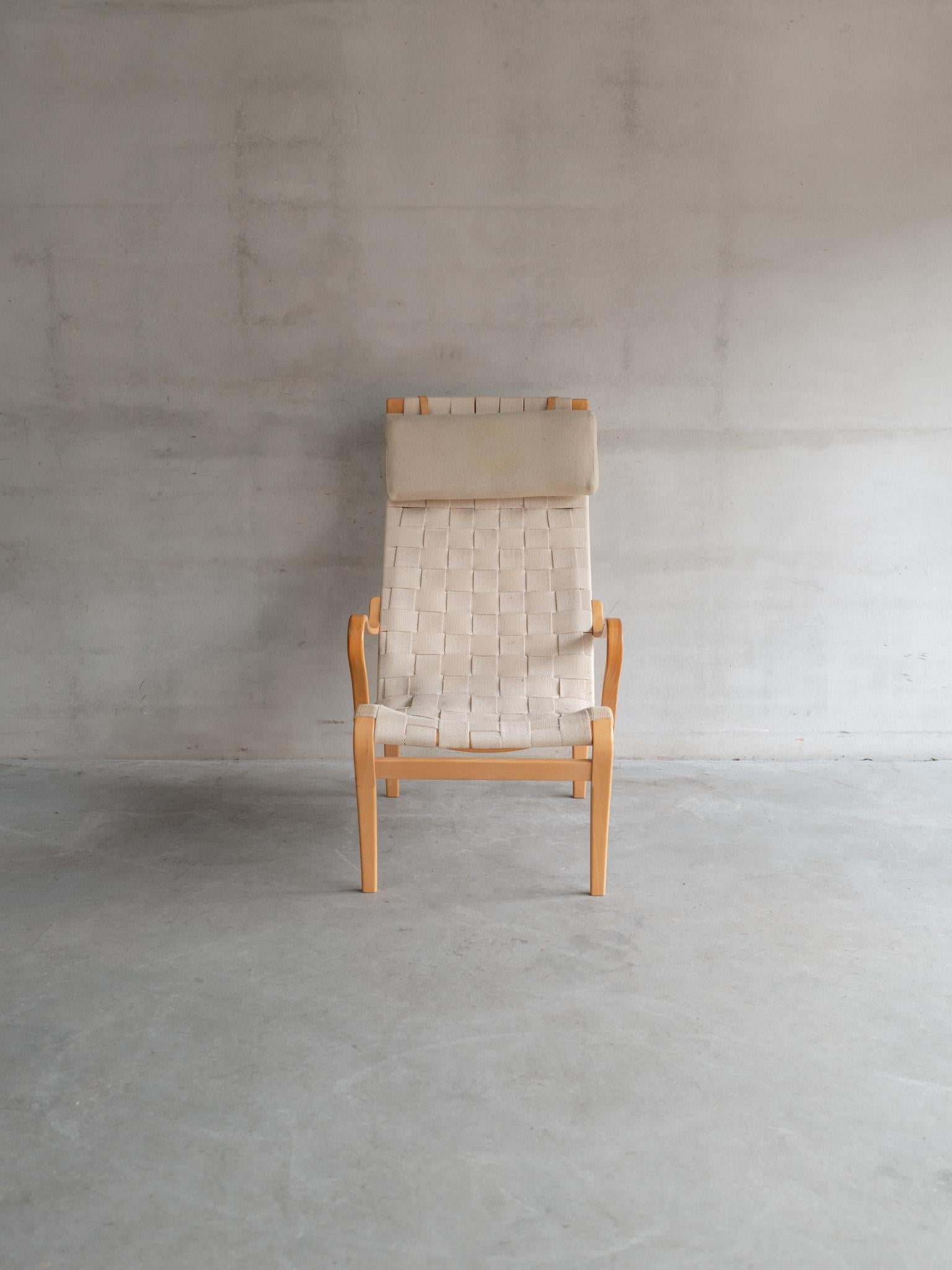 Esta particular Silla Mina de Bruno Mathsson data de los años 50 e ilustra maravillosamente la dedicación del diseñador a la comodidad y la forma reflexiva. Diseñado por primera vez en 1934, el modelo Mina presenta un armazón de madera curvada