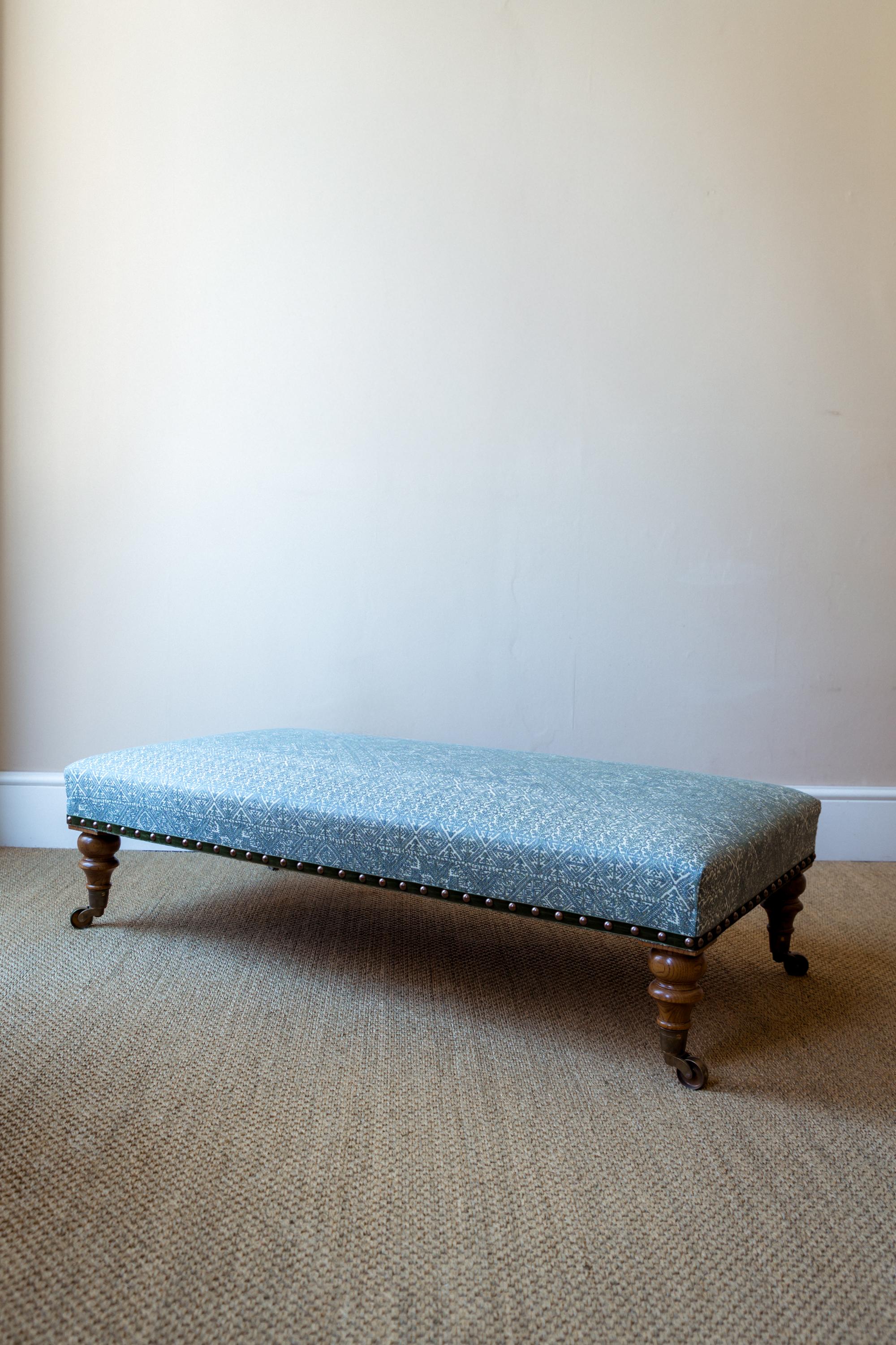 Der Moreton Footstool, der dem Design der Hocker von Howard & Sons aus dem späten 19. Jahrhundert nachempfunden ist, wird in England in traditioneller Handarbeit nach höchsten Standards gefertigt. Das Gestell aus Buche steht auf handgedrechselten