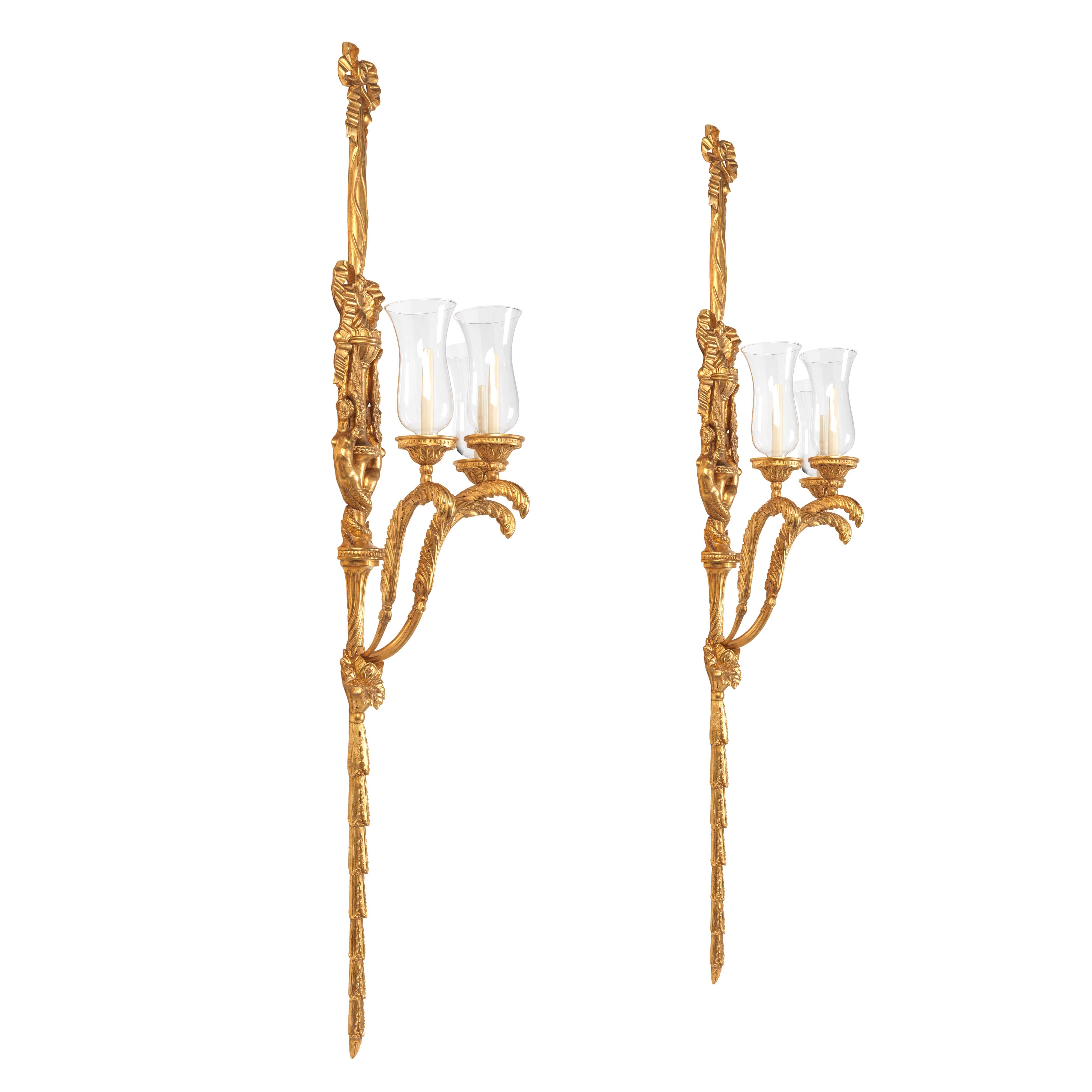 An exceptional pair of grand scale Neo-Classical design carved and water gilded wall lights. Bespoke sizing, design adaptations and finishing available. Please note we are currently working to a 30-36 week lead time. 
