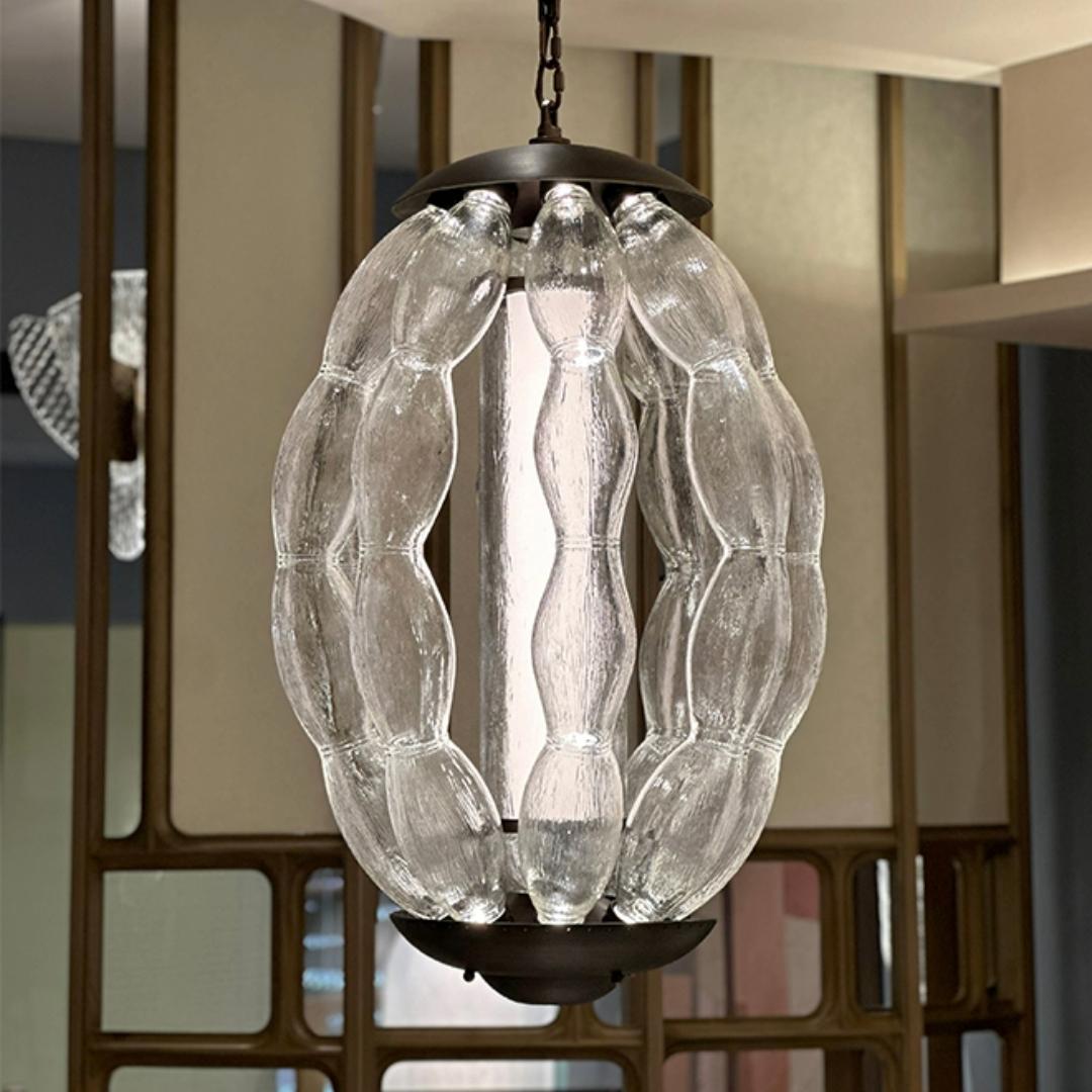 featuring a central sphere surrounded by eight glass orbs on gracefully arched arms, the pendant design with interplay of sleek metal and frosted glass creates a captivating visual contrast, casting a warm, inviting glow.