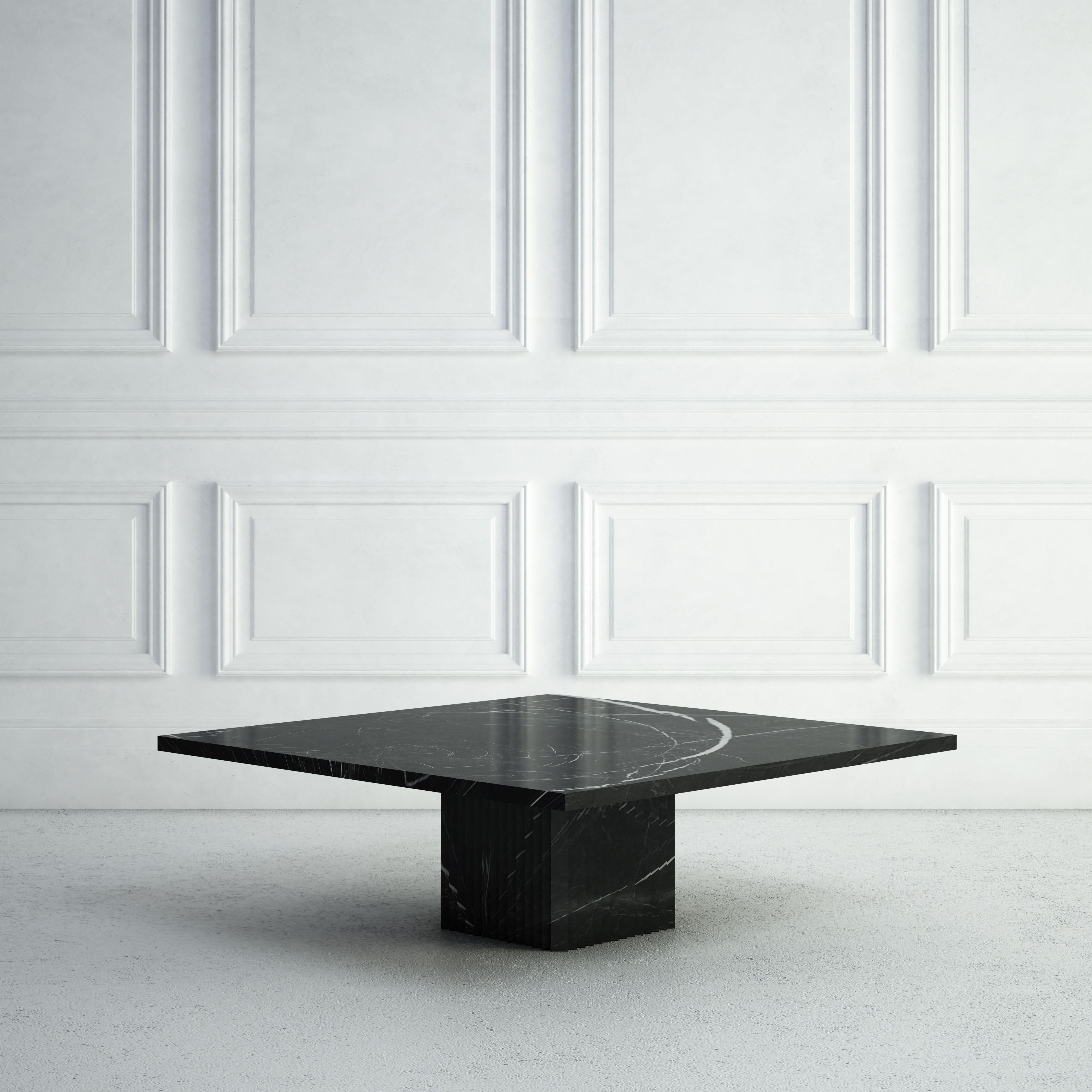 The Odette is a graceful modern coffee table.  The top is made from an elegant thin square stone slab, with the base, also square, showing vertical carved peaked ridges on each of its four sides.  The same stone is used throughout.  The table is