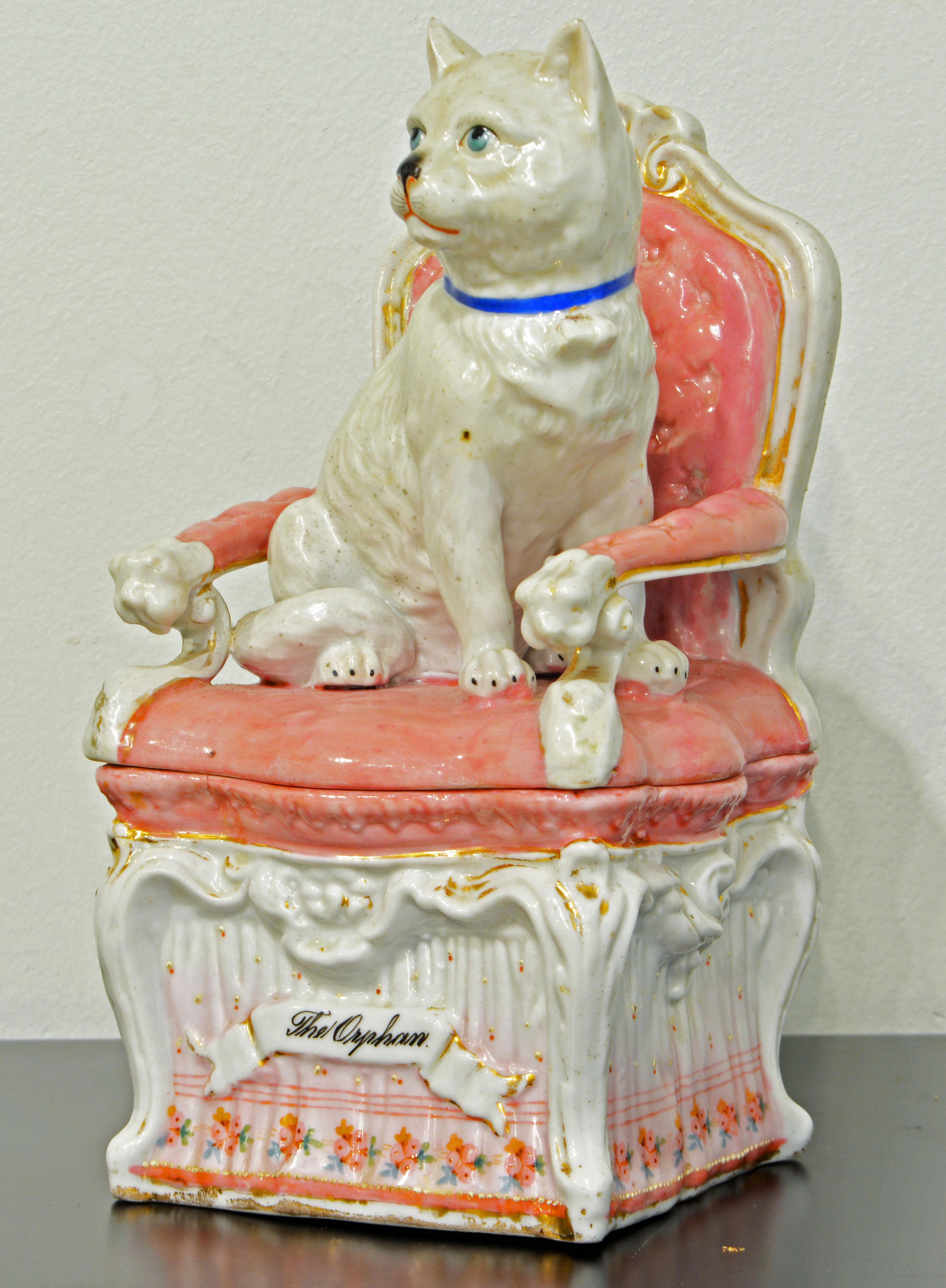 This lovely late 19th century Staffordshire figure of a white cat with blue eyes and collar sitting proudly on a fine rococo chair consists of a top and a bottom part creating a nice little space for keepsakes.
