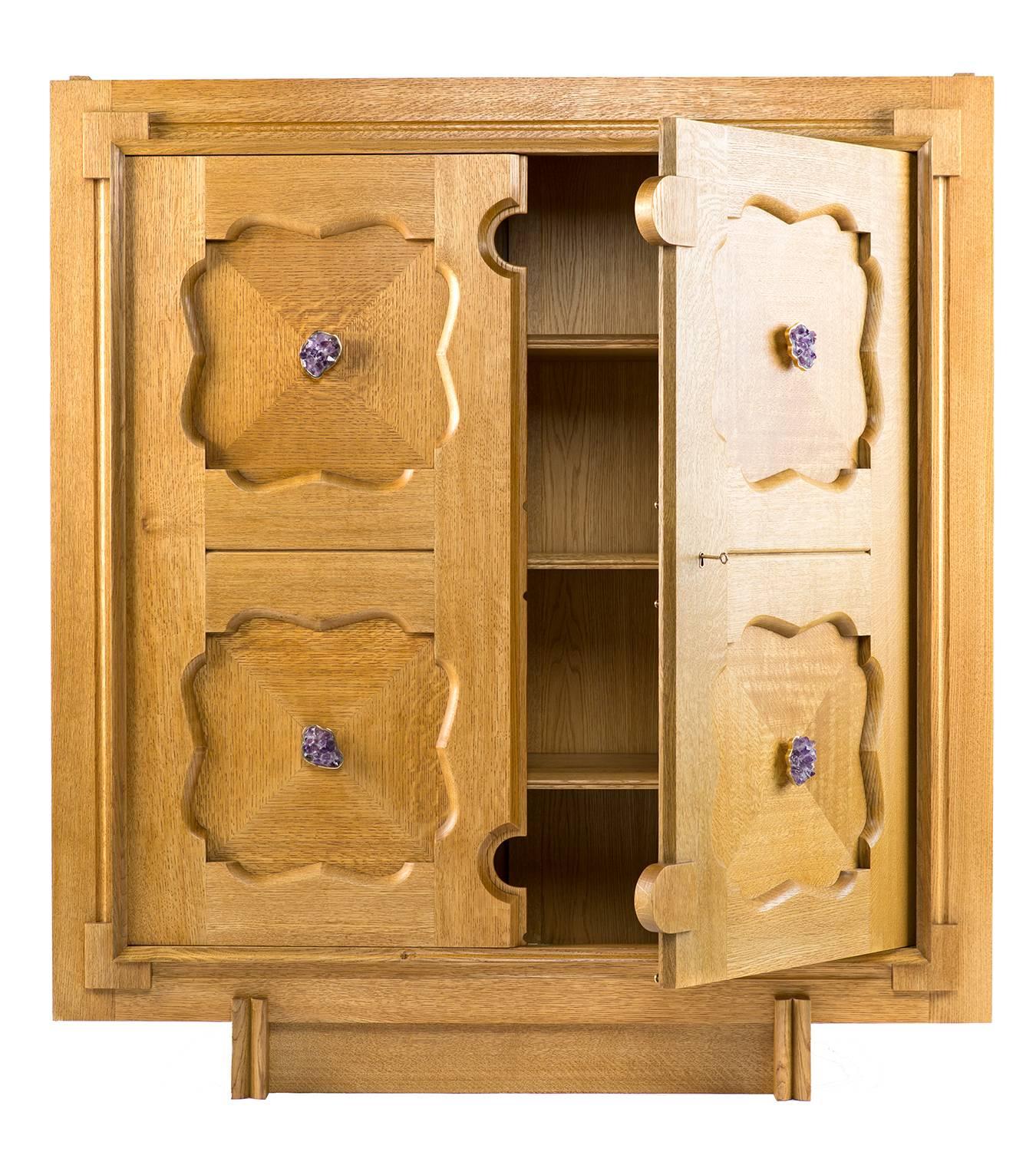The Parterre cabinet in white oak with natural finish, amethyst clusters, and unlacquered brass hardware. The main body of the cabinet rests on a removable oak stand. Paneled doors secure with a custom brass and steel cremone bolt. 

The paneled