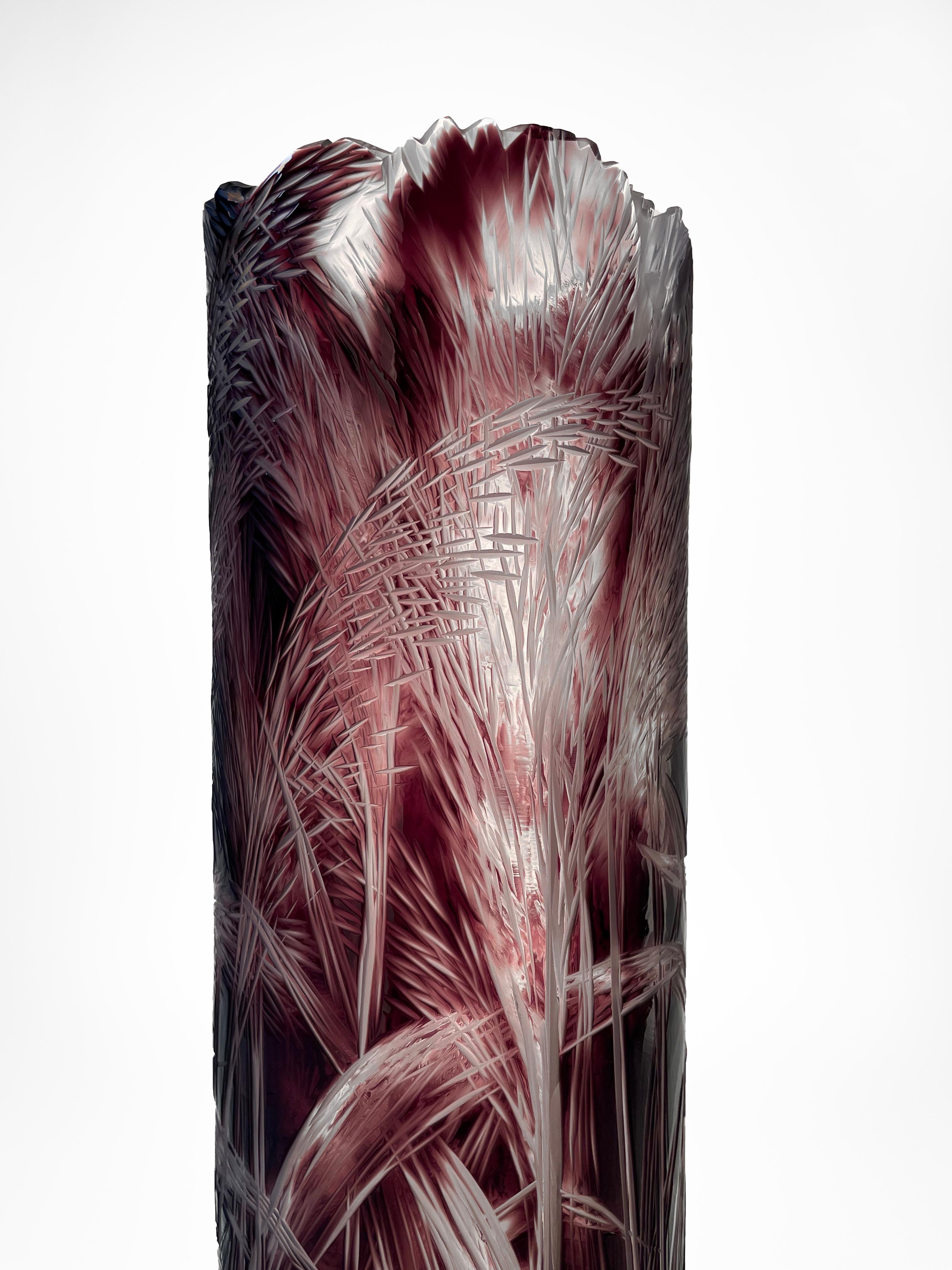 Vase is made of overlayed glass and having cylindrical shape. The organic hand-engraved motif is engraved through the purple solid glass all the way to the crystal glass layer. The engraving depicts reeds, natural stalks. The engraving is created