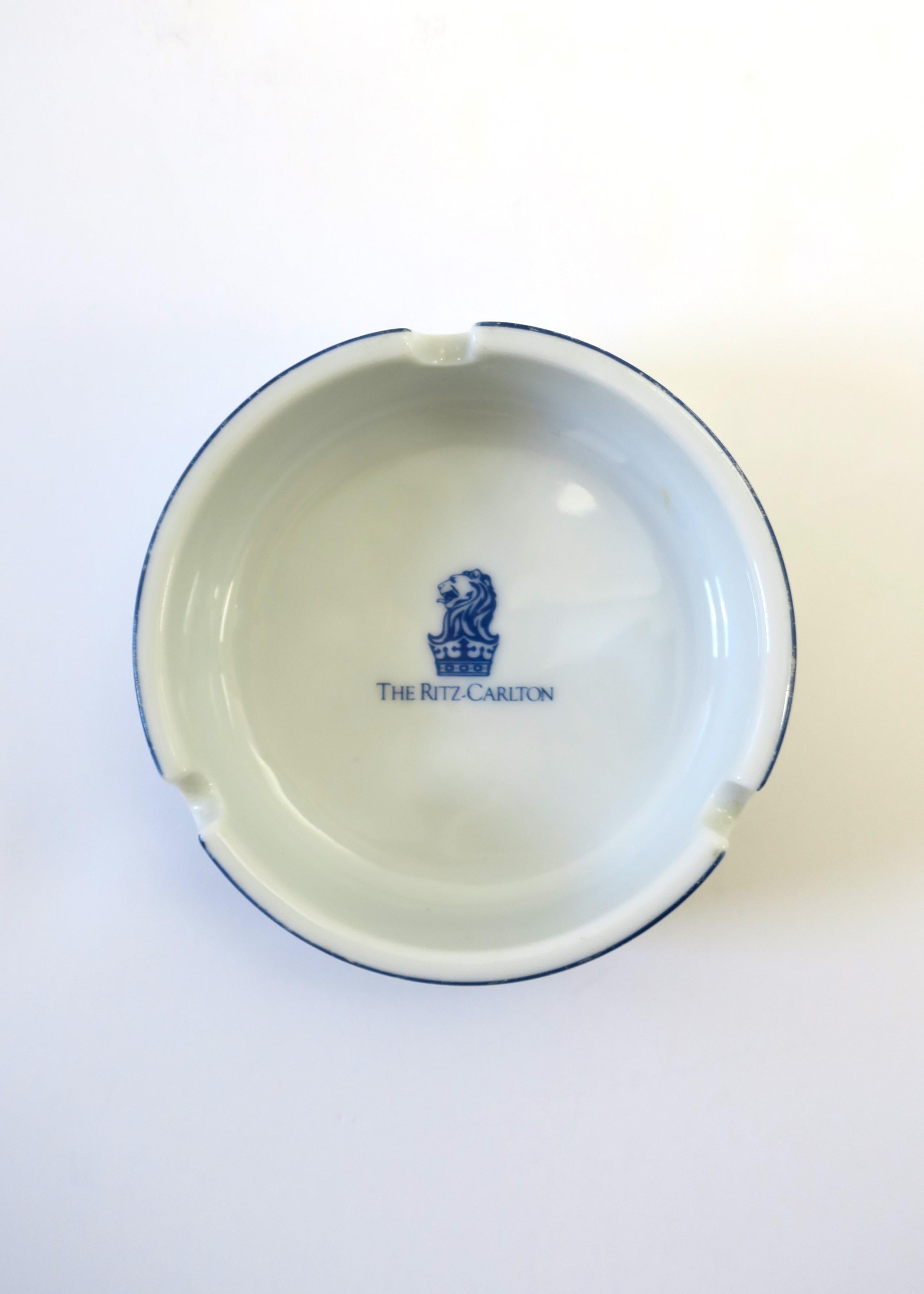 A blue and white ceramic ashtray from the iconic 'The Ritz Carlton' hotel, circa late-20th century. Iconic Lion and crown at center. Great for its intended use, indoors or out, on a bar, cocktail table, etc., or a bedside, vanity, etc., as a jewelry