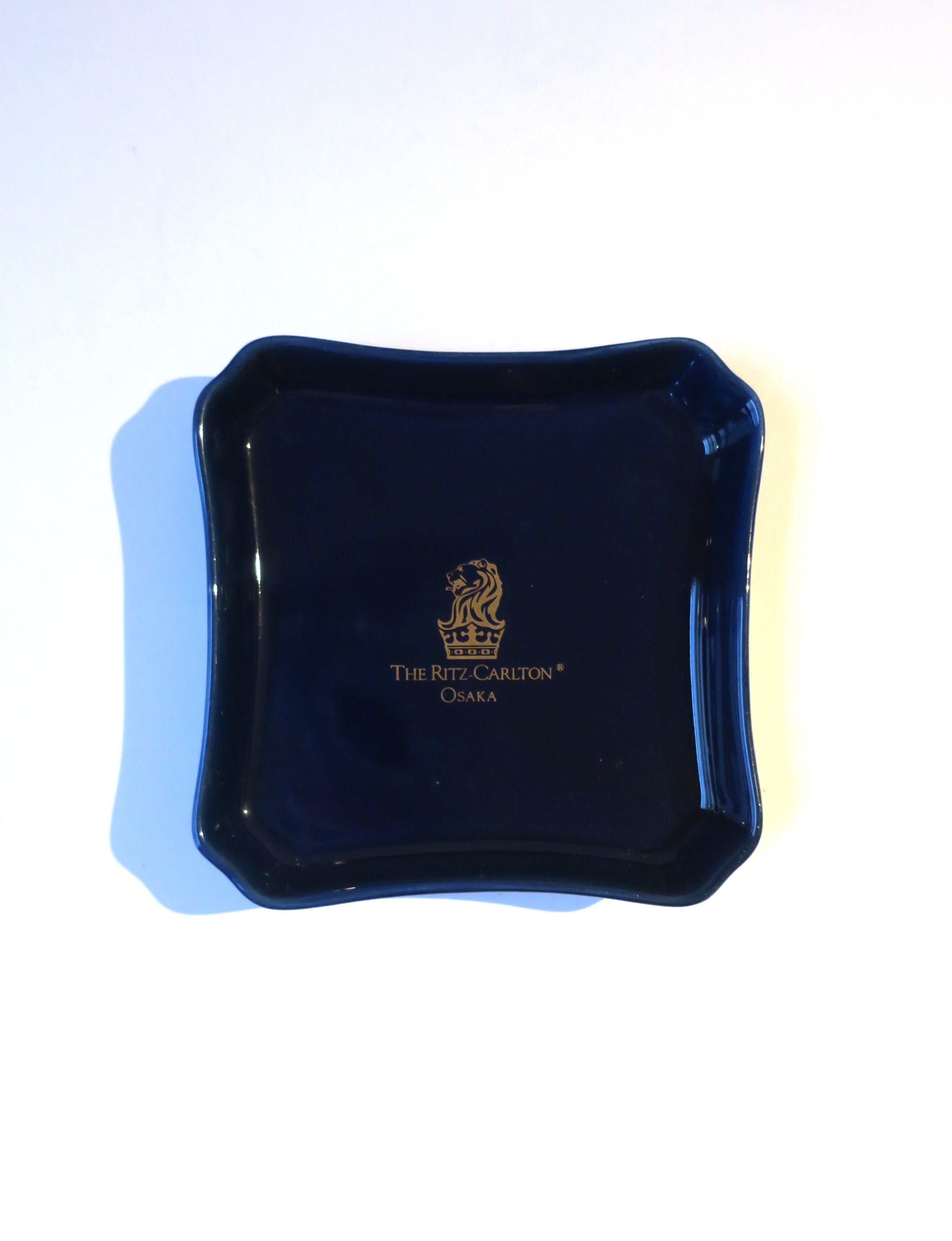 A dark blue porcelain jewelry dish from The Ritz Carlton, Osaka, Japan, circa late-20th century. Iconic Ritz Carlton Lion head and crown at center, 'Osaka Japan', below, both in gold. A great piece to hold jewelry (as demonstrated) or other small