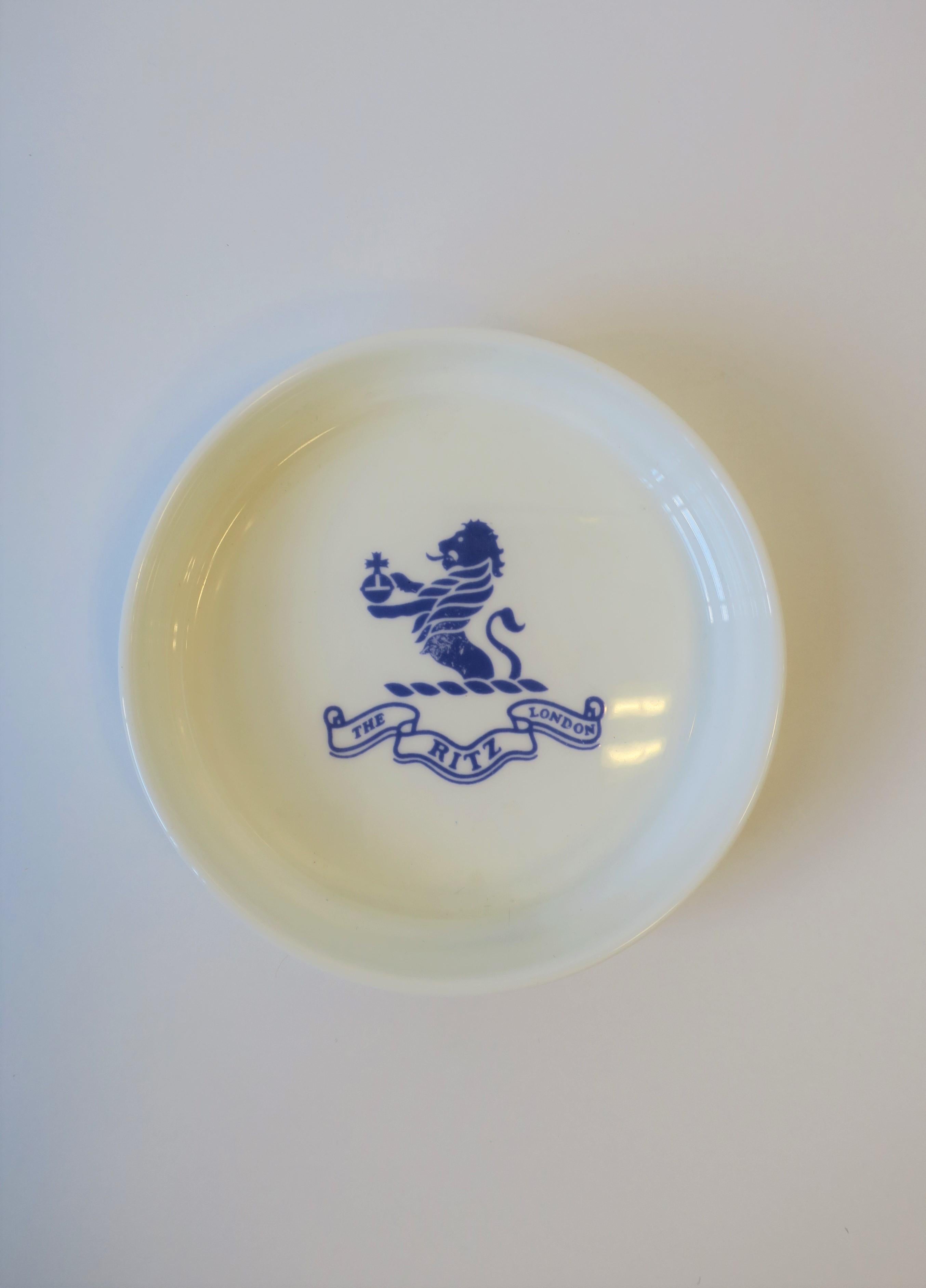 From 'The Ritz London' a round blue and white porcelain jewelry dish with Lion crest detail. Piece also makes a great catch-all for desk, vanity, nightstand area, etc. Piece is fine bone-china porcelain made by Royal Daulton, England, as marked on