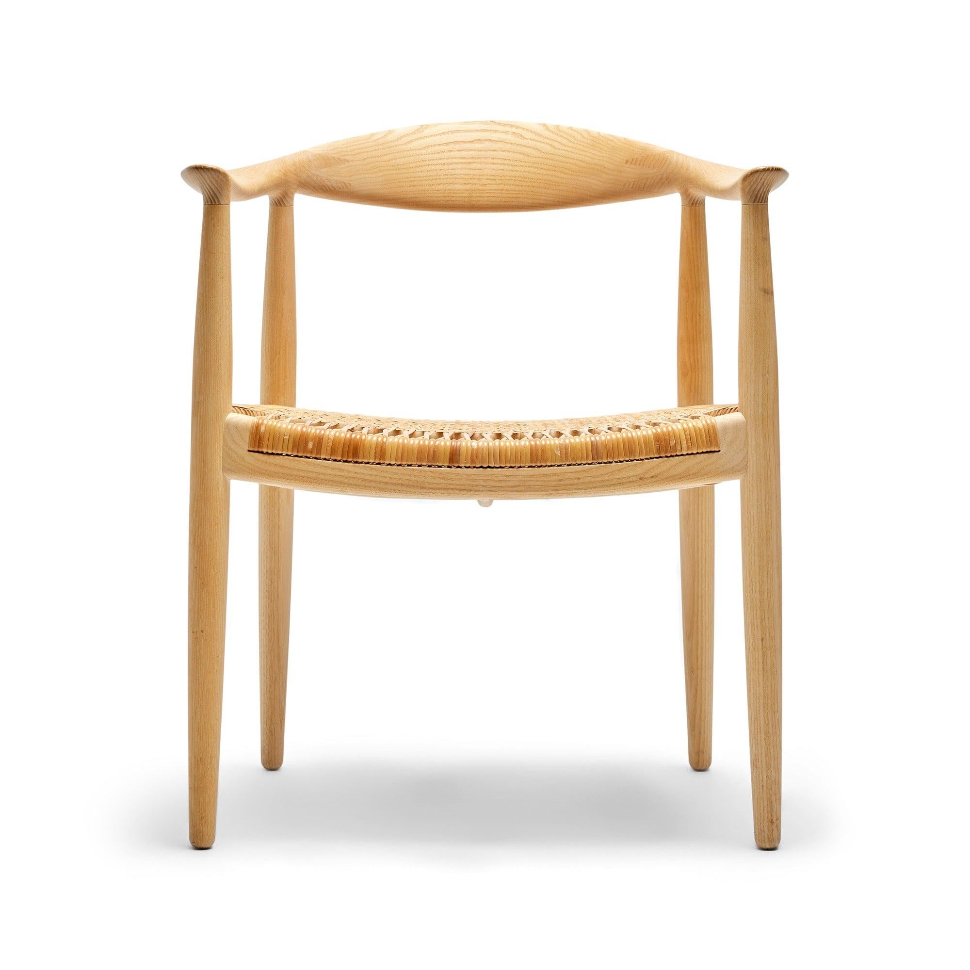 La chaise ronde PP501 est dotée d'un dossier et d'accoudoirs sculptés en frêne et d'une assise en rotin tressé à la main.