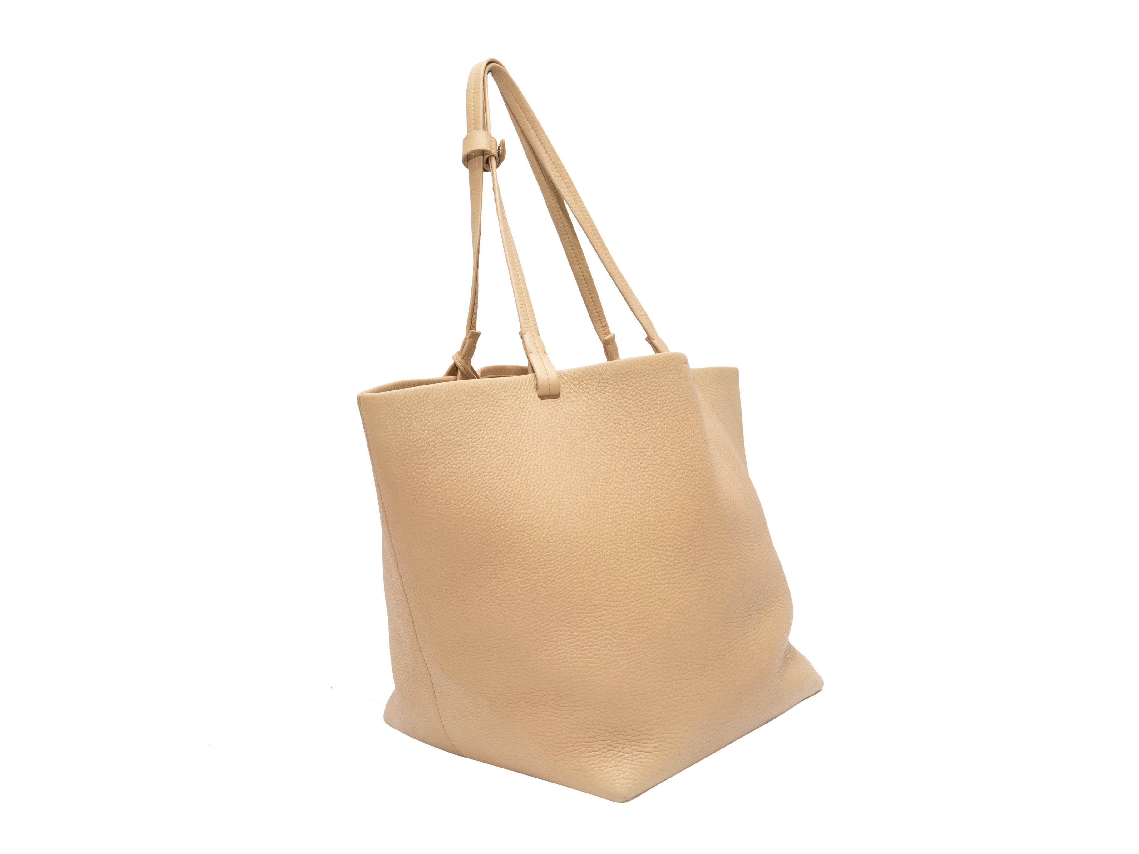 Product Details: Beige The Row Leather Tote Bag. This bag features a leather body, silver-tone hardware, dual flat top handles, and matching interior pouch. 18