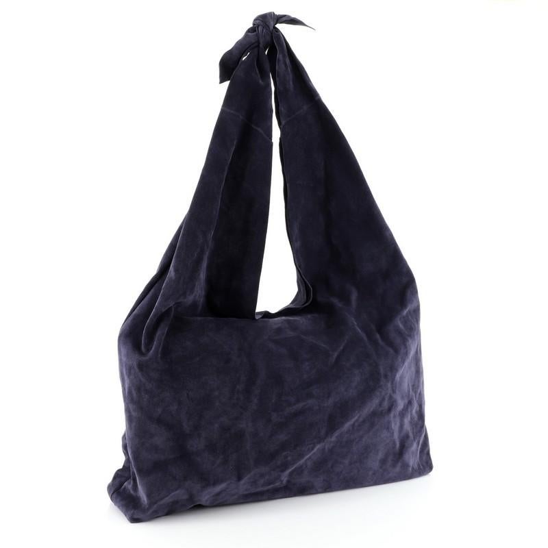This The Row Bindle Knot Hobo Suede, crafted in blue suede, features knotted shoulder strap, dipped open top, and silver-tone hardware. It opens to a blue suede interior with zip pocket. 

Estimated Retail Price: $1,190
Condition: Great. Minimal
