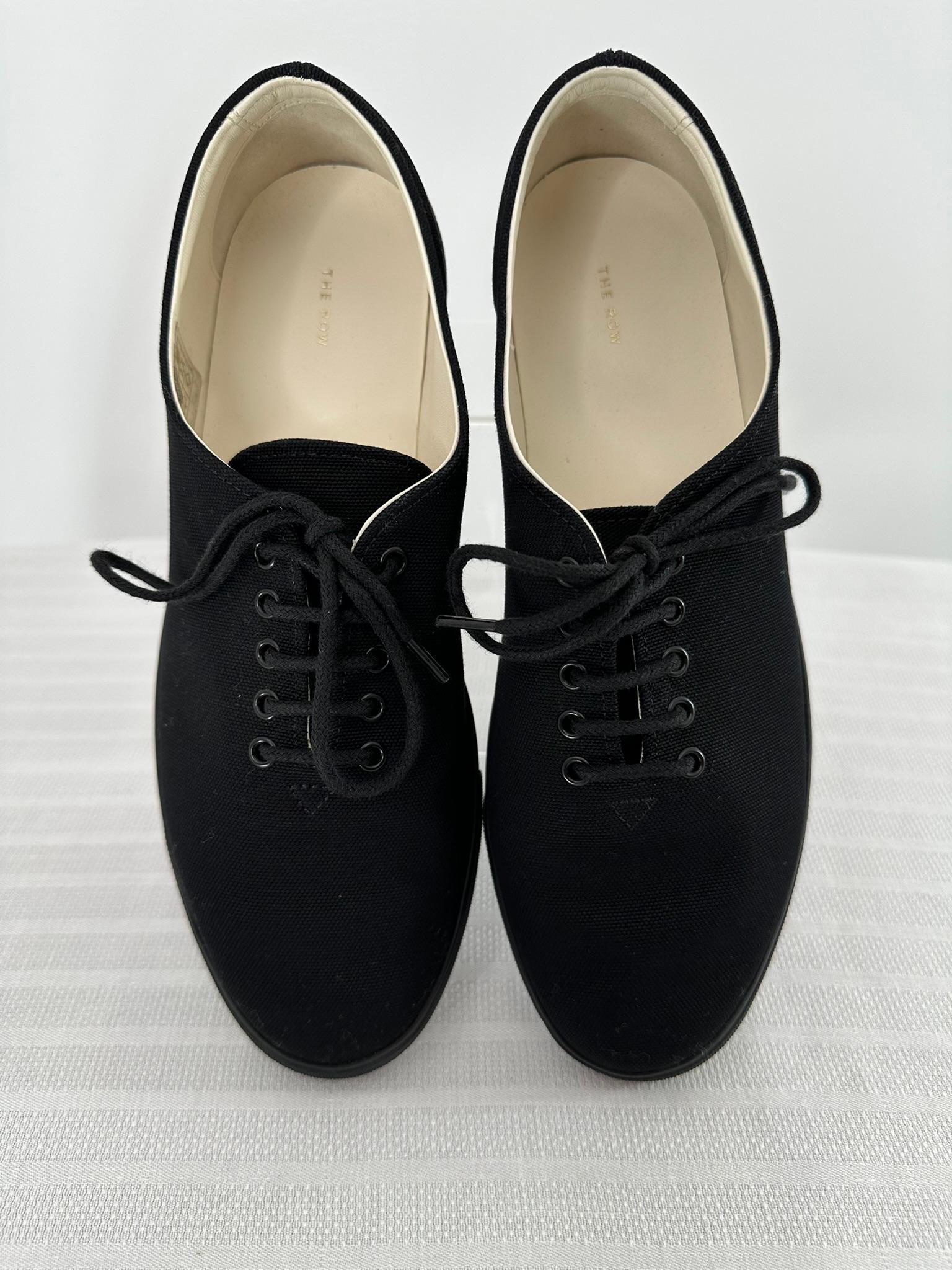 The Row, scarpe da ginnastica allacciate in tela nera, foderate in pelle bianca, con la taglia 37. 
Punta tonda, sneakers con suola piatta in gomma, lacci e cravatta per chiudere. Ottime scarpe casual. Sembrano a malapena, se mai indossati. 
Le
