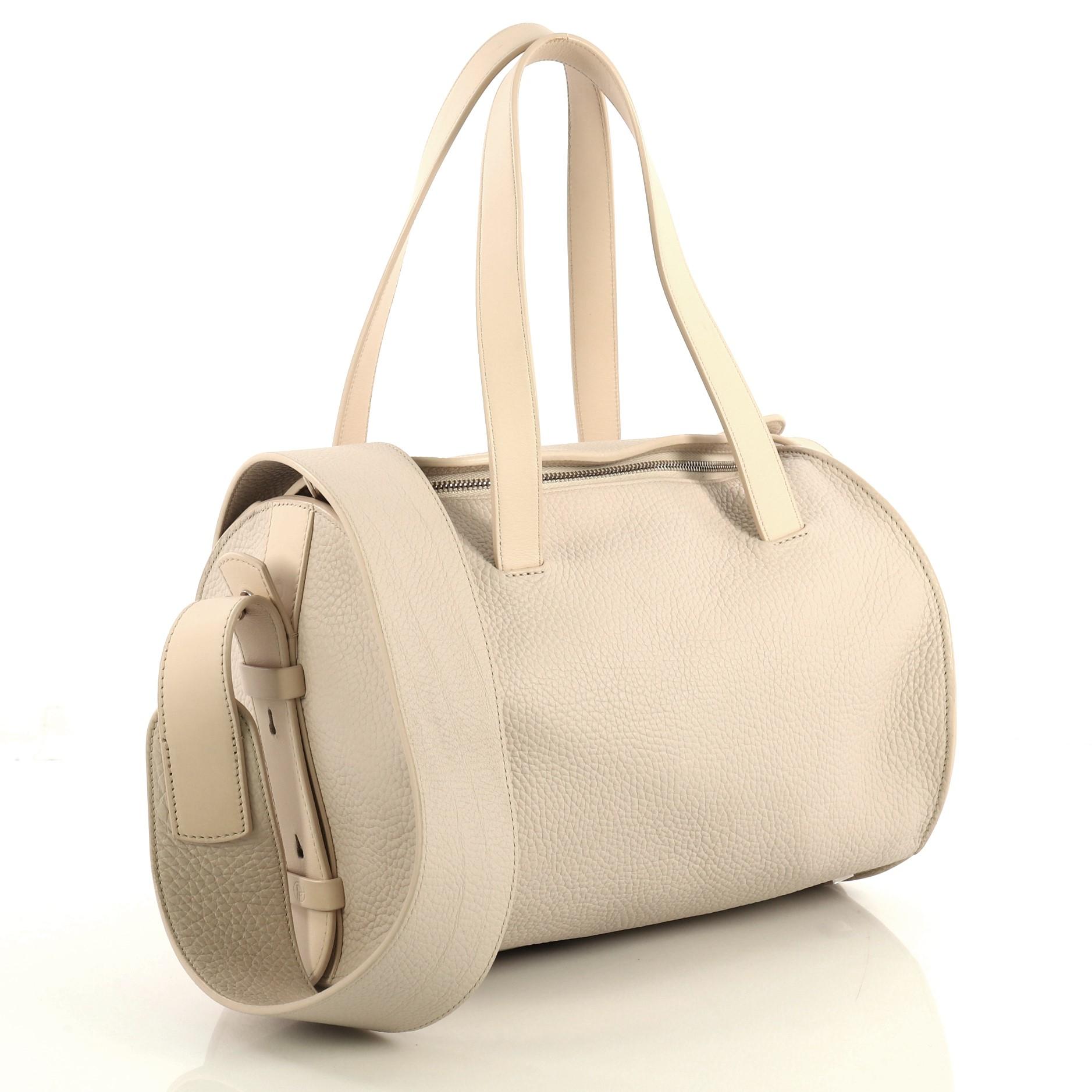 This The Row Drum Shoulder Bag Leather 10, crafted from neutral leather, features dual flat handles, protective base studs, and silver-tone hardware. Its zip closure opens to a neutral fabric interior with zip and slip pockets. 

Estimated Retail