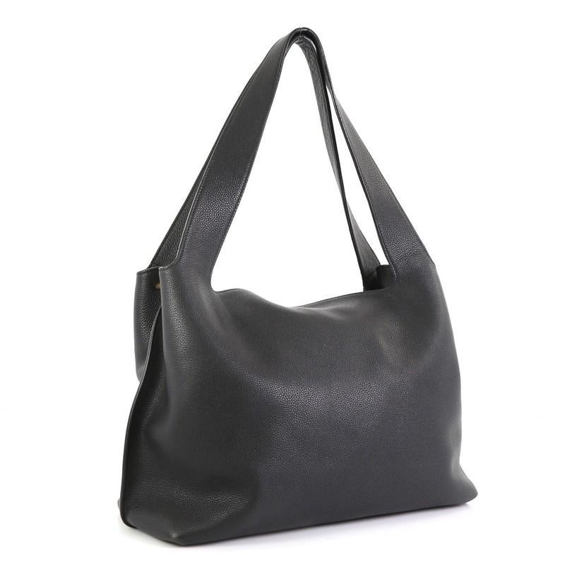 This The Row Duplex Hobo Leather, crafted in black leather, features dual flat leather straps and aged gold-tone hardware . Its top zip closure and magnetic closure opens to a black suede and neutral fabric interior with two open compartments and