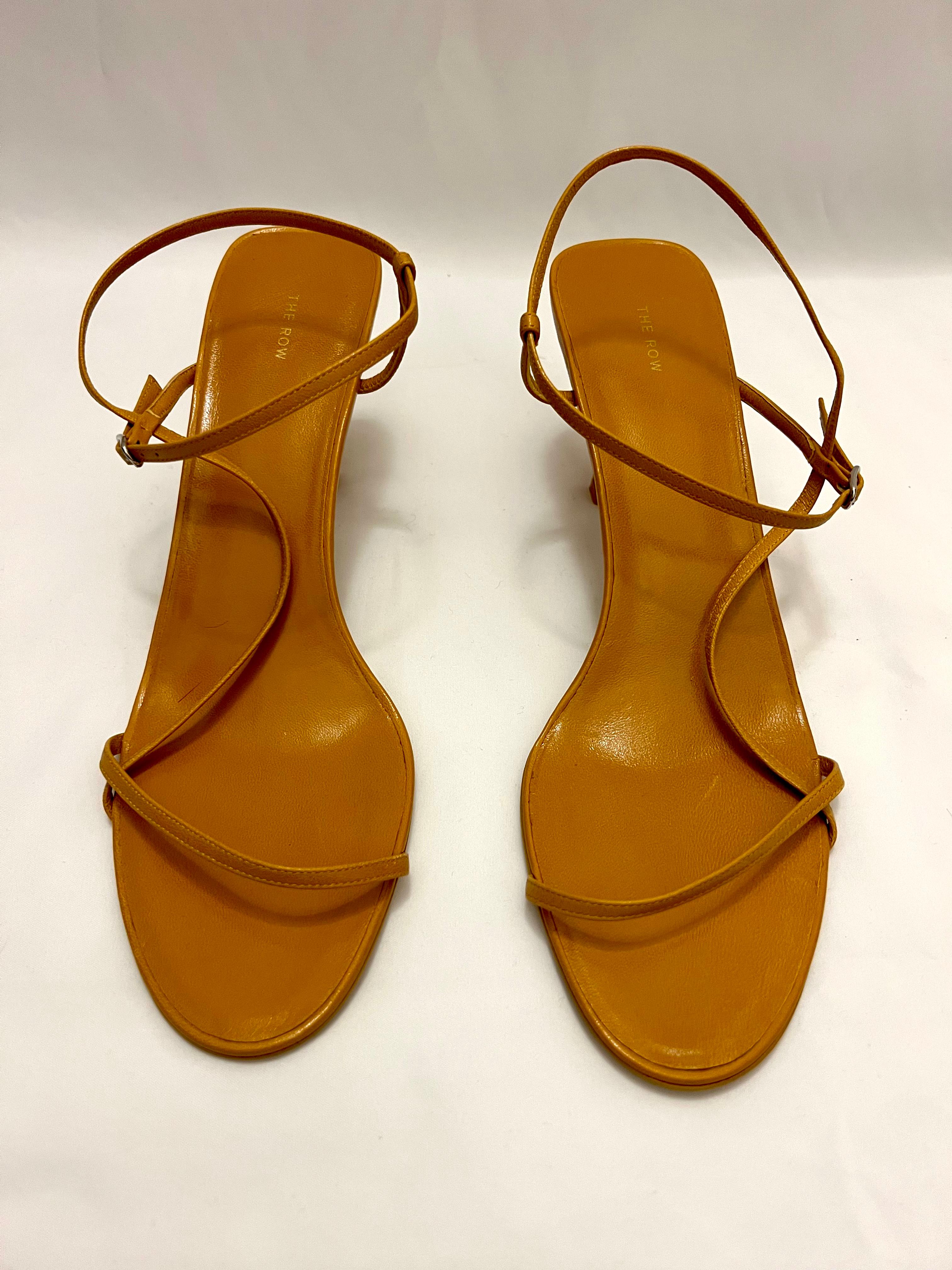 The sandals are made out of yellow mustard leather. They feature thin straps and asymmetrical design with adjustable ankle strap and 2.5” block heel. The shoes are brand new. Est. Retail is $790.