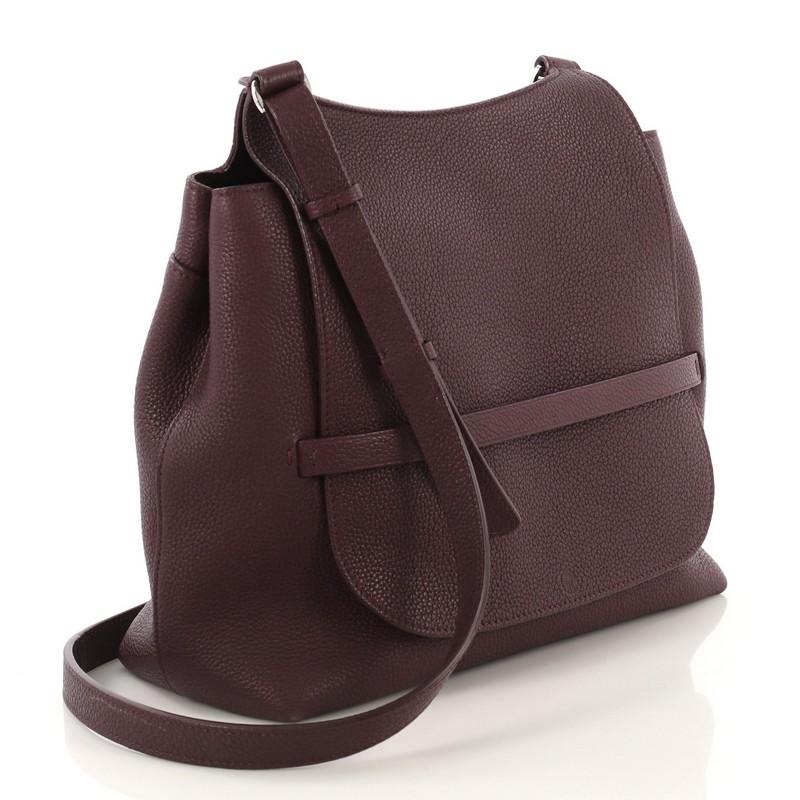This The Row Sideby Shoulder Bag Leather, crafted from purple leather, features adjustable flat leather shoulder strap, slip-through front-flap closure, exterior back slip pocket, and silver-tone hardware accents. Its slip-through closure opens to a