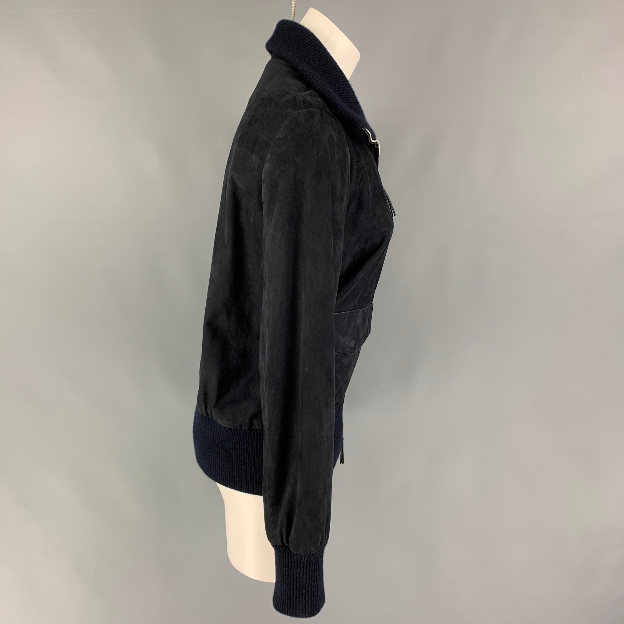 THE ROW jacket comes in a navy lamb skin suede featuring a wool blend ribbed hem, high neck, flap pockets, and a full zip up closure. Made in Italy. 

Very Good Pre-Owned Condition.
Marked: S

Measurements:

Shoulder: 16 in.
Bust: 38 in.
Sleeve: