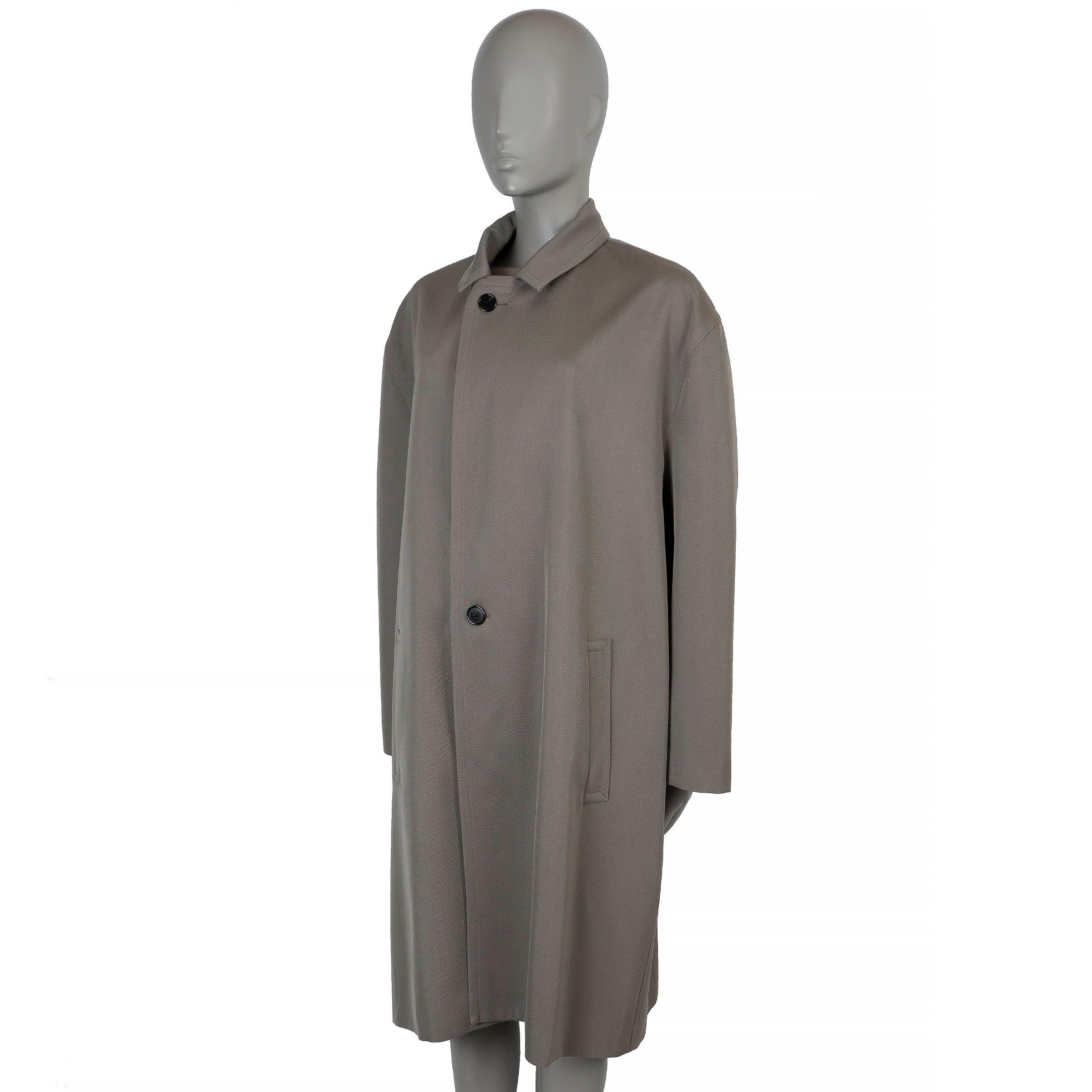 Ce manteau The Row Clancy, 100% authentique, est confectionné en laine sergée taupe (100%) et coupé dans une silhouette oversize avec des épaules tombantes et une longueur au genou. Il présente des revers crantés, deux poches passepoilées et une