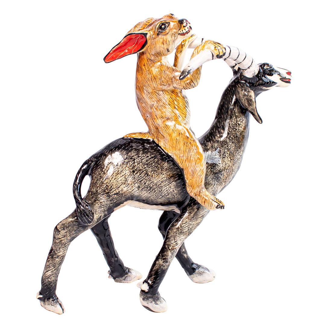 Sable & Rabbit Rider Sculpture
Handmade Ceramic – One of a Kind

This whimsical ceramic sculpture features a wide-eyed rabbit clutching the curled horns of a graceful sable antelope, riding with joyful abandon. With exaggerated expressions and
