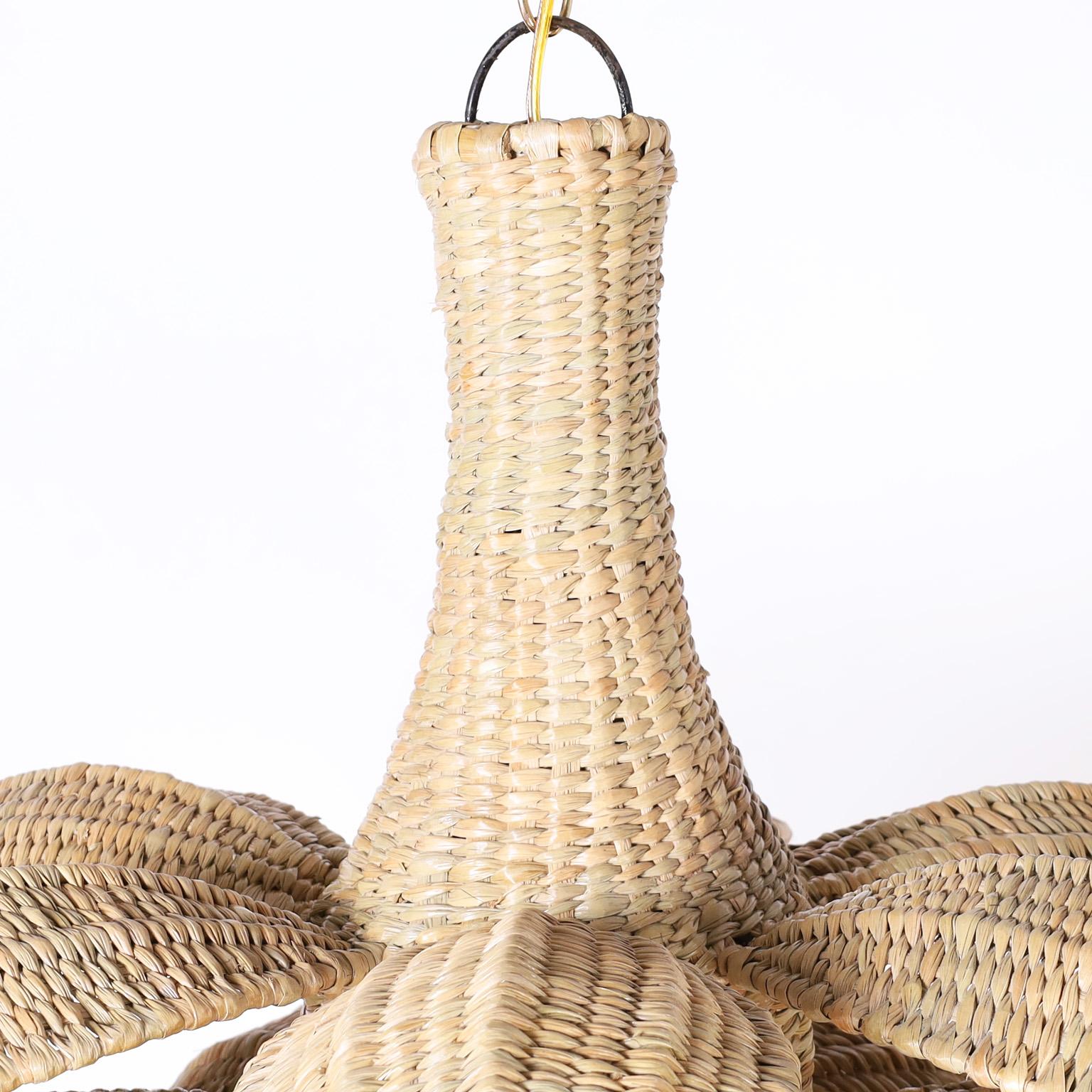 The Sanibel, a wicker palm leaf or lotus pendant light fixture crafted in chuspata reed tightly and expertly woven over a sturdy metal frame with three tiers of palm leaves, exclusively designed and offered by F.S. Henemader antiques as part of the