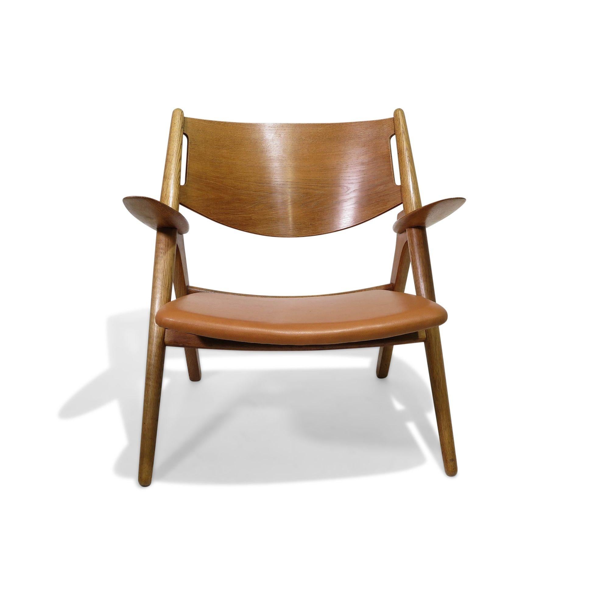 Model CH28, “Sawbuck” chair designed by Hans Wegner and produced by Carl Hansen in Denmark, 1951. The chair features a simple and elegant design, with a distinctive X-shaped frame that gives it a modern, yet timeless, appearance. The chair's