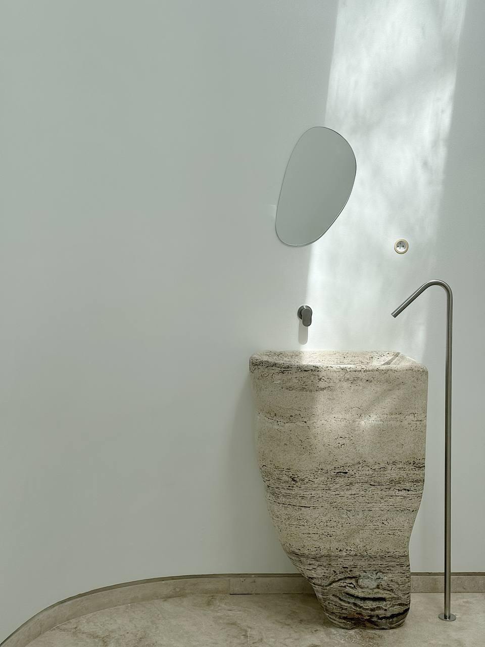 This free-standing vanity designed by L'atelier Arman Safavi an crafted from opulent silver travertine, showcases an exquisite blend of modern sophistication and timeless beauty.

The vanity’s fluid lines and sculptural form are meticulously