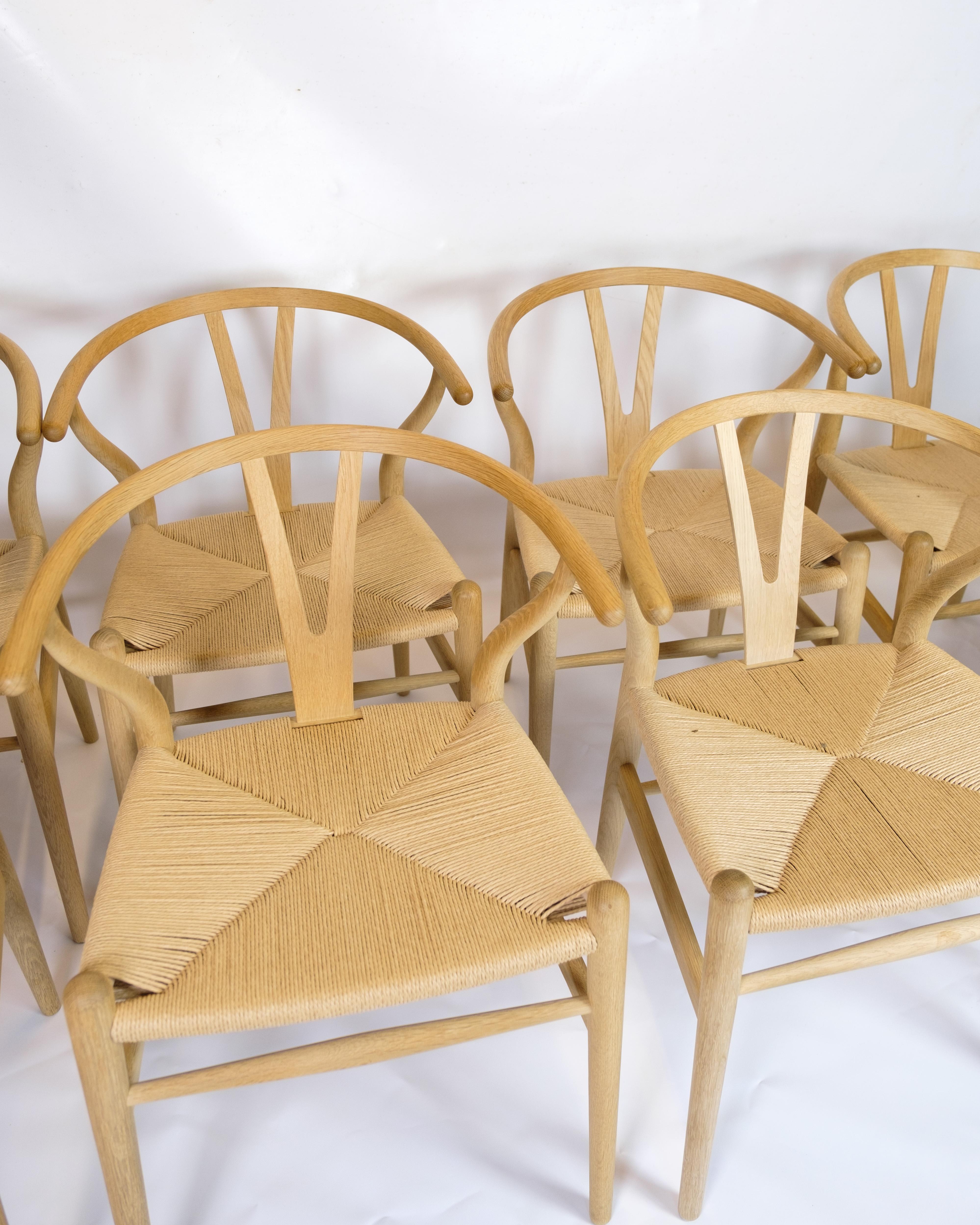 The set of four Y-chairs, model CH24, is an iconic design created by the famous Danish architect and furniture designer Hans J. Wegner in 1950. The chairs are crafted in oak, which adds a natural warmth and elegance to their