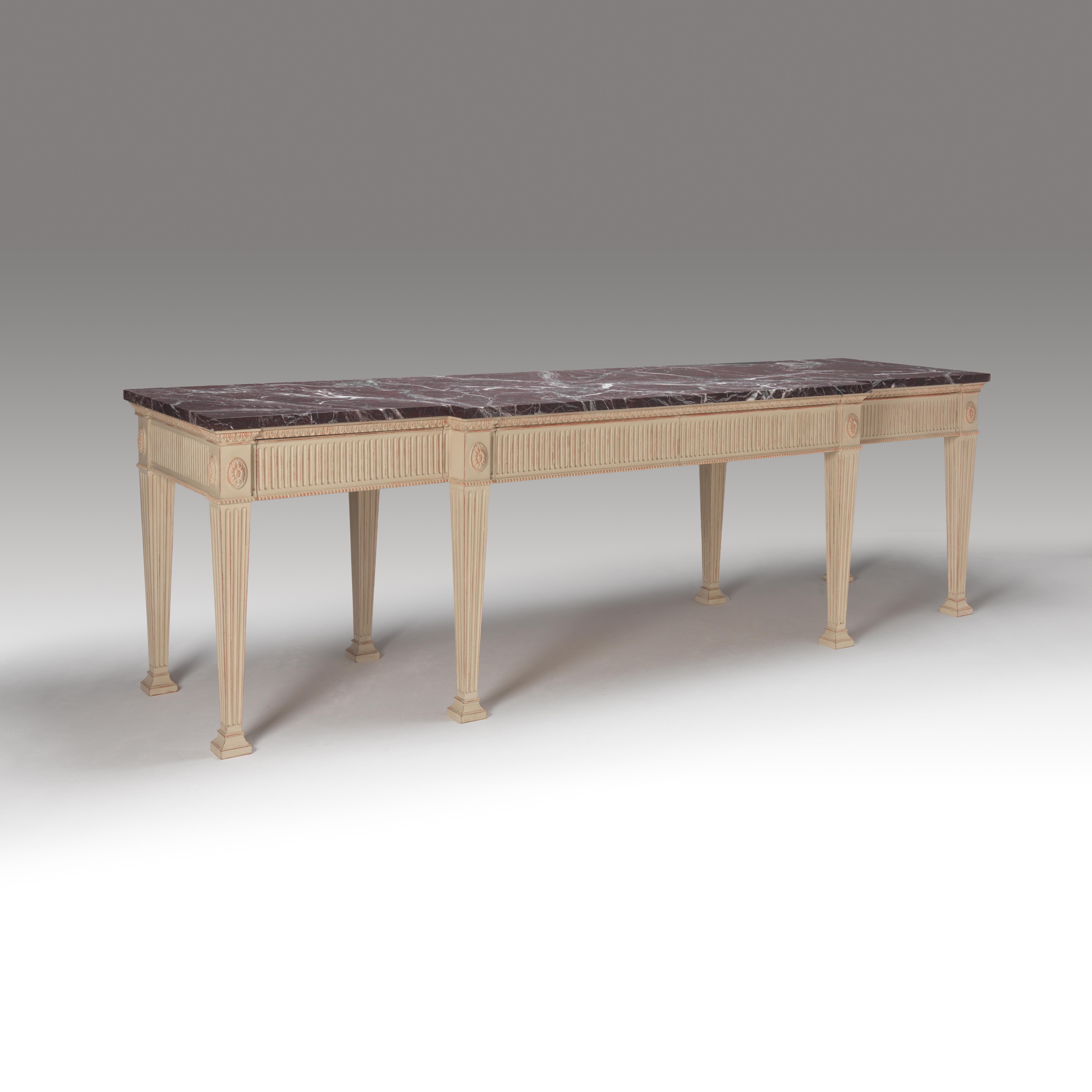 Consola de generosas proporciones de diseño Jorge III pintada por especialistas. La consola tiene patas cuadradas estriadas que terminan en un pie de bloque, el friso con estrías a juego, molduras de cuentas y detalles de patera redonda.
El friso
