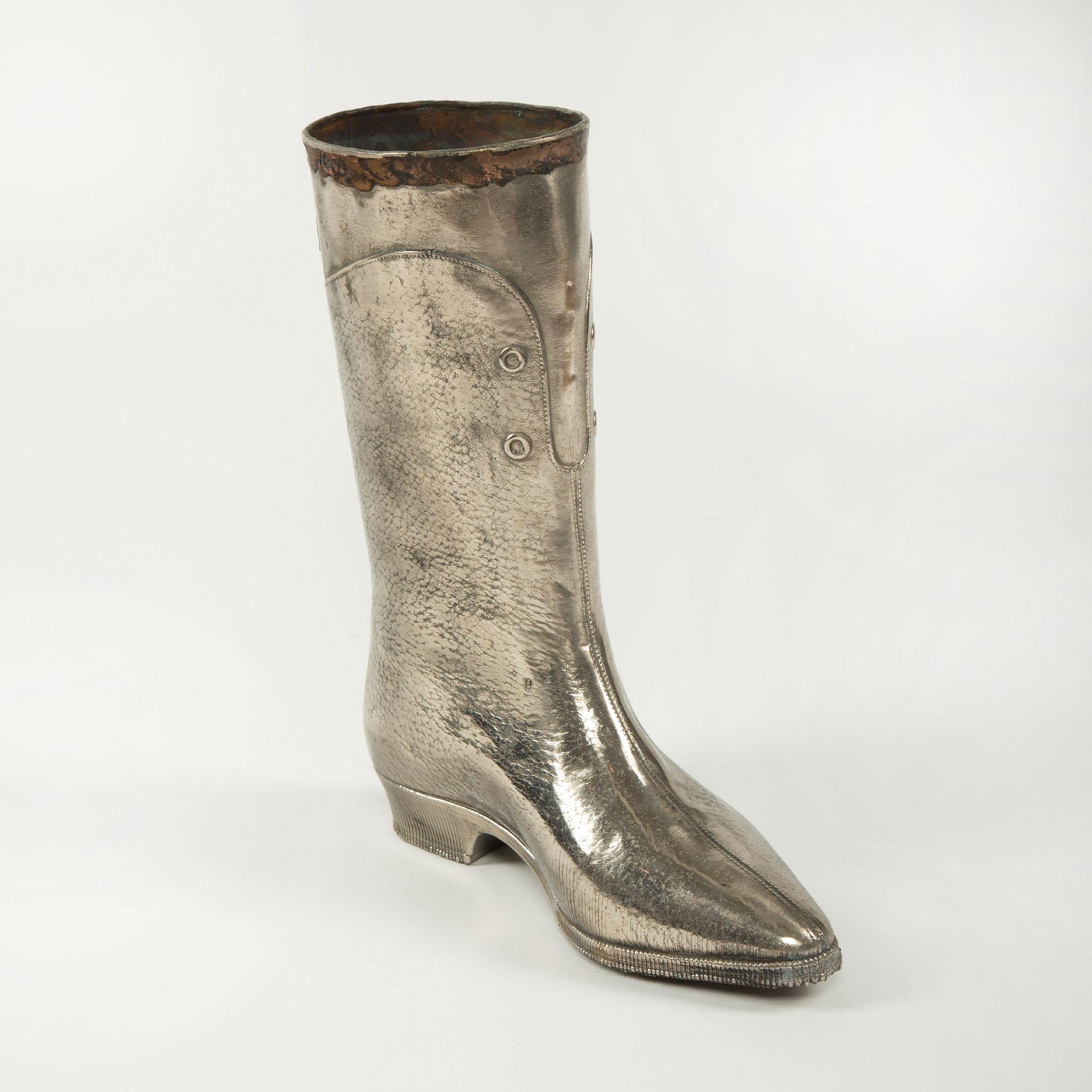 Decorative vintage metal boot form, finely cast to replicate the details of a boot, complete with textured surface, stitched seams, and molded sole. This striking piece, likely intended as a decorative object or possibly a trade display, bears