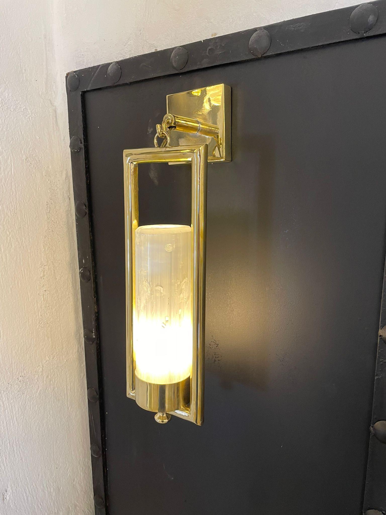 This beautiful hanging wall light is made of both brass and selenite. It is comprised of a selenite cylinder sat within a tubular rectangle brass frame, with a light fitted in the bottom of the selenite cylinder. The frame and light then hang from a