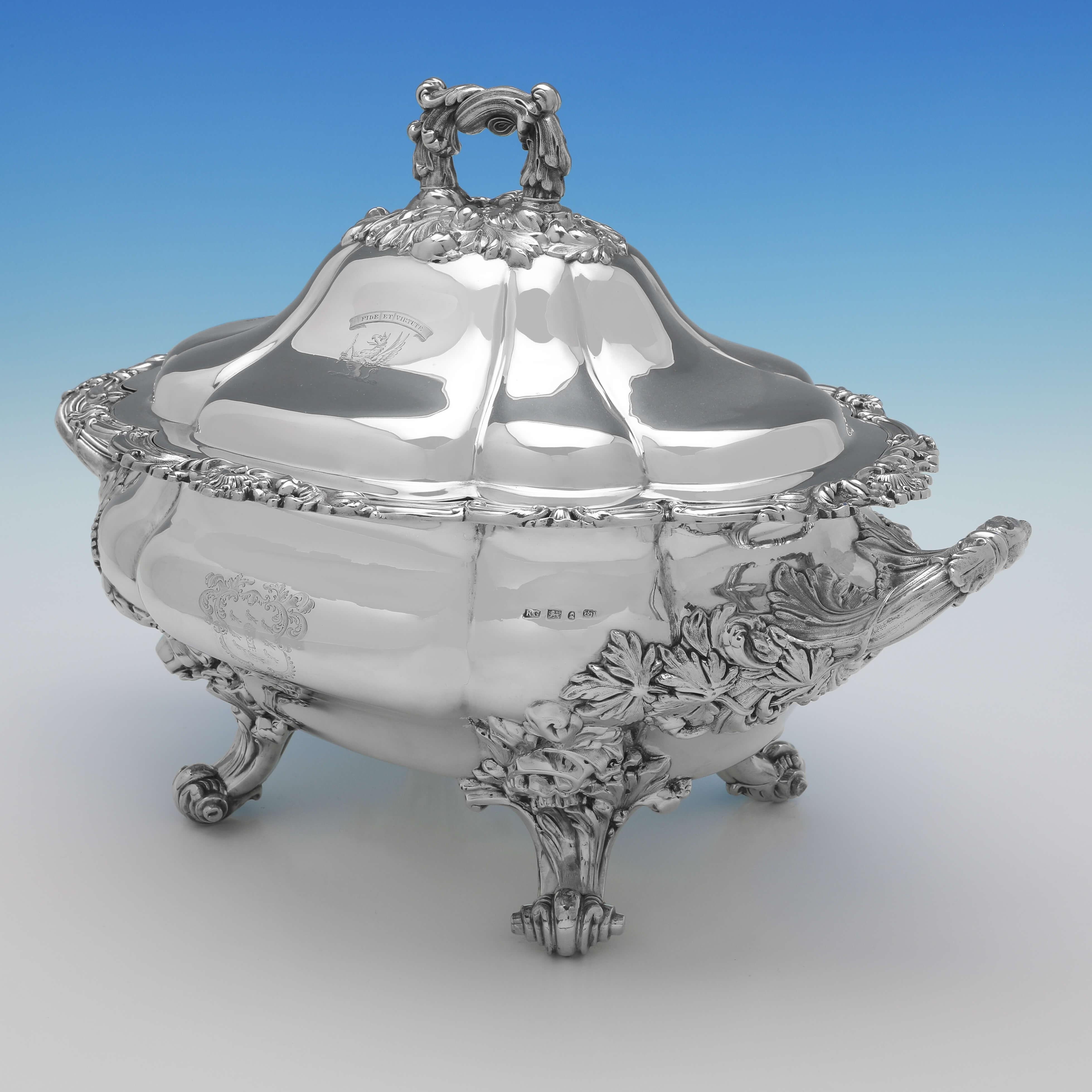 Hallmarked in Sheffield in 1833 by Robert Gainsford, this striking, Antique Sterling Silver Soup Tureen, is in the Regency taste, featuring ornate cast feet and handles, and heraldic engraving. 

The soup tureen measures 12.25