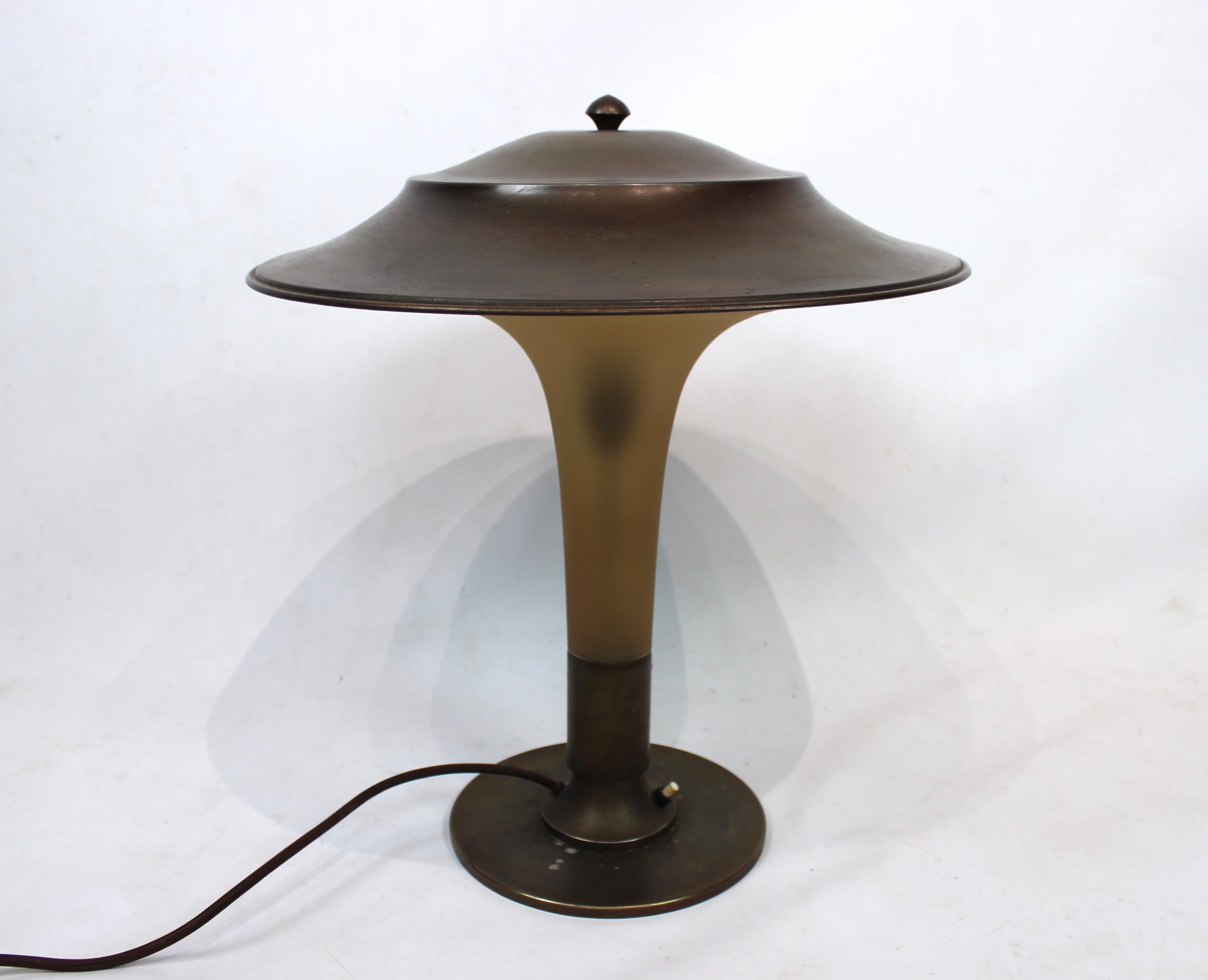 The Torch lamp with stem of amber colored glass and foot and shade of patinated brass. The lamp is by Fog and Mørup from the 1930s.