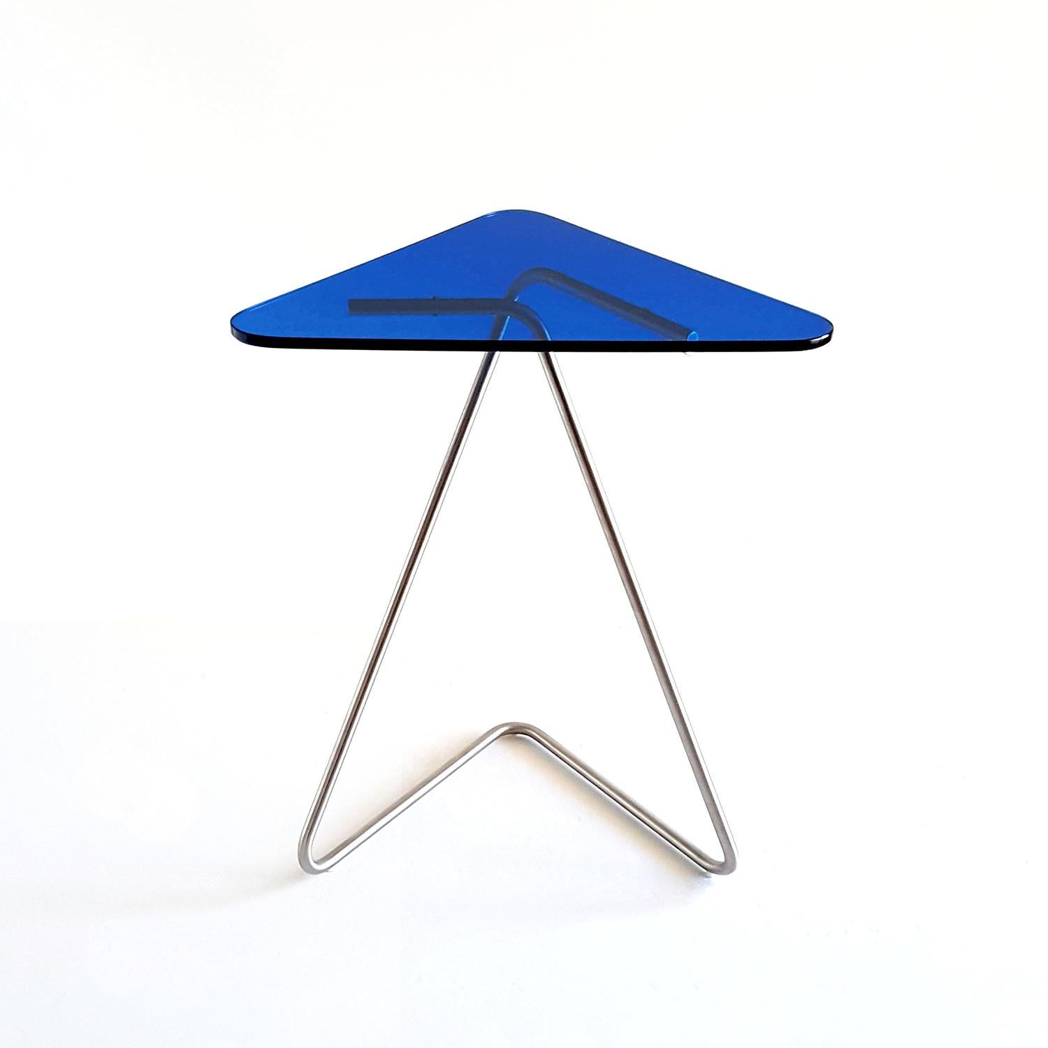 The triangle side table by Rita Kettaneh
Dimensions: The base: brushed stainless steel
 optionally plated with copper or brass
 The top: acrylic
Materials: H 49.5 x W 41 x D 9.5 cm
Weight: 2.6 Kg

Colors and finishes: 
Stainless finish: