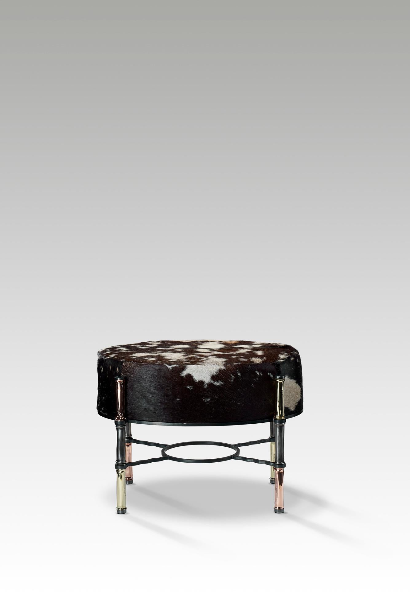 The trophy stool is unexpected and eye-catching, it is perfect as an ottoman or seating at a vanity or console.

Hand shaped, polished brass, copper and blackened steel details are paired with luxurious goat hide upholstery to create a modern