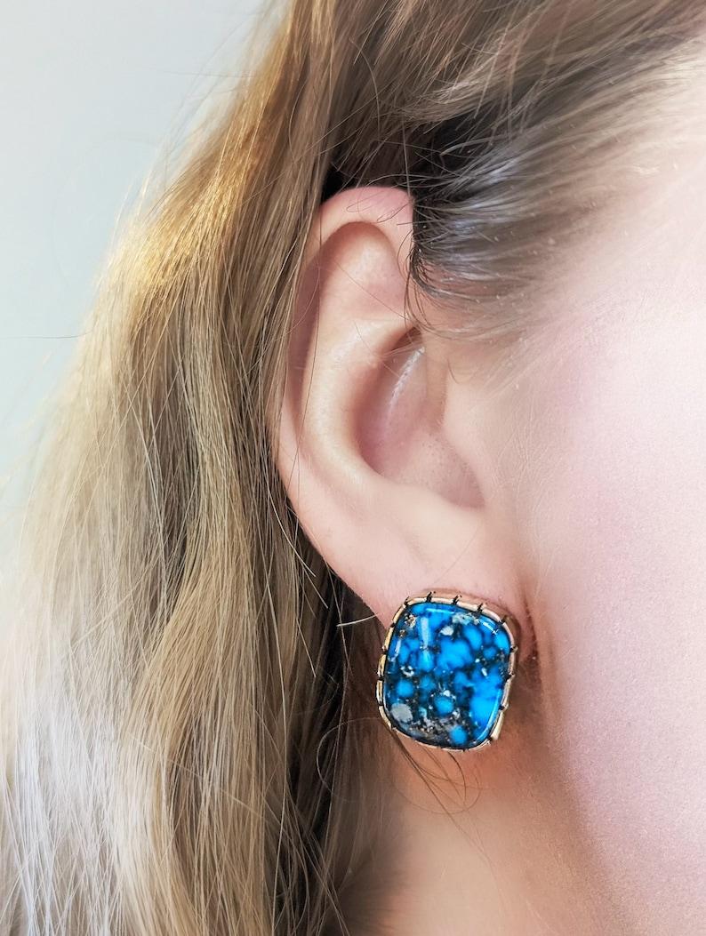 Discover our handcrafted earrings by silversmith Rob Sherman. These earrings feature cowboy and bohochic aesthetics. Perfect for those who appreciate a blend of traditional and modern styles! Each pair is uniquely mismatched, featuring blue