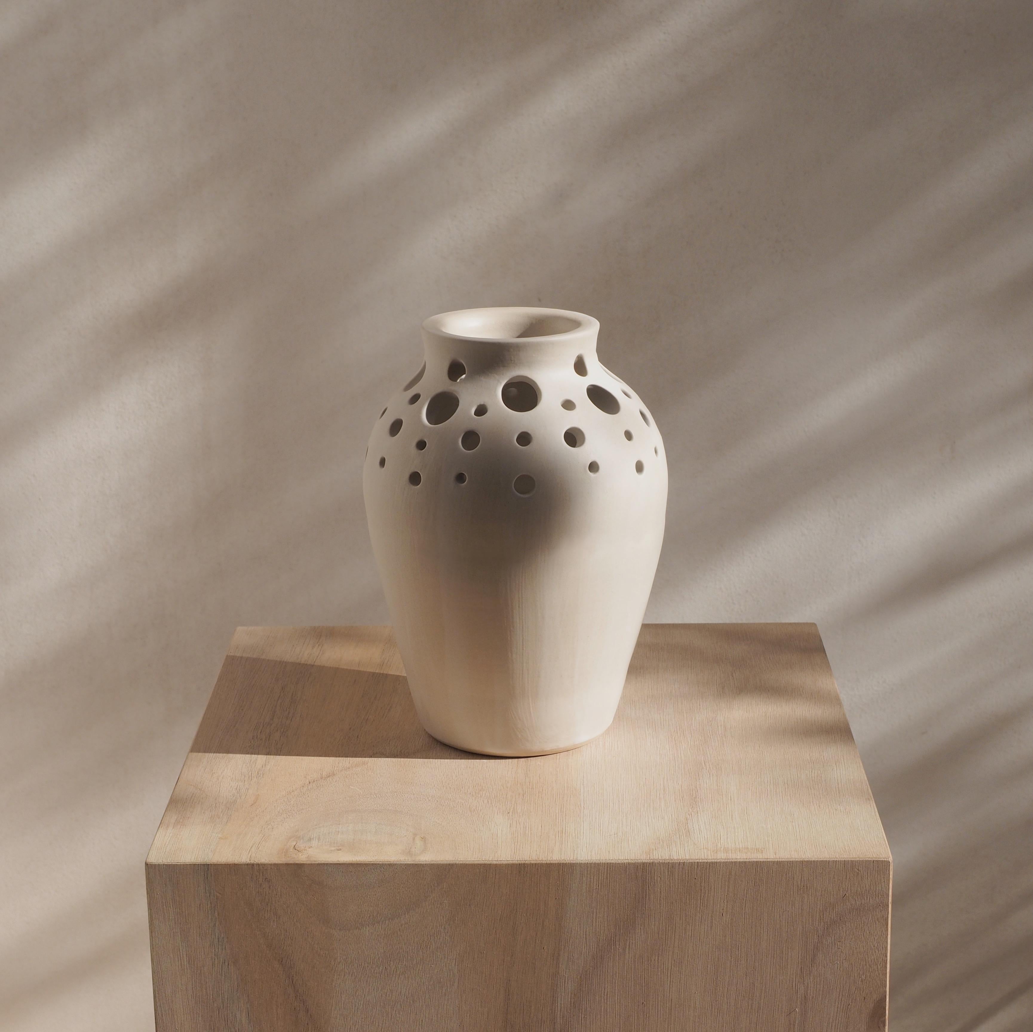 This unique vase has been created by Laura de Grinyo in her workshop in Ibiza. 
For this piece the potter's wheel has been used to create the initial base. 
During the initial drying stage of the clay a pattern of hand made carved holes of different