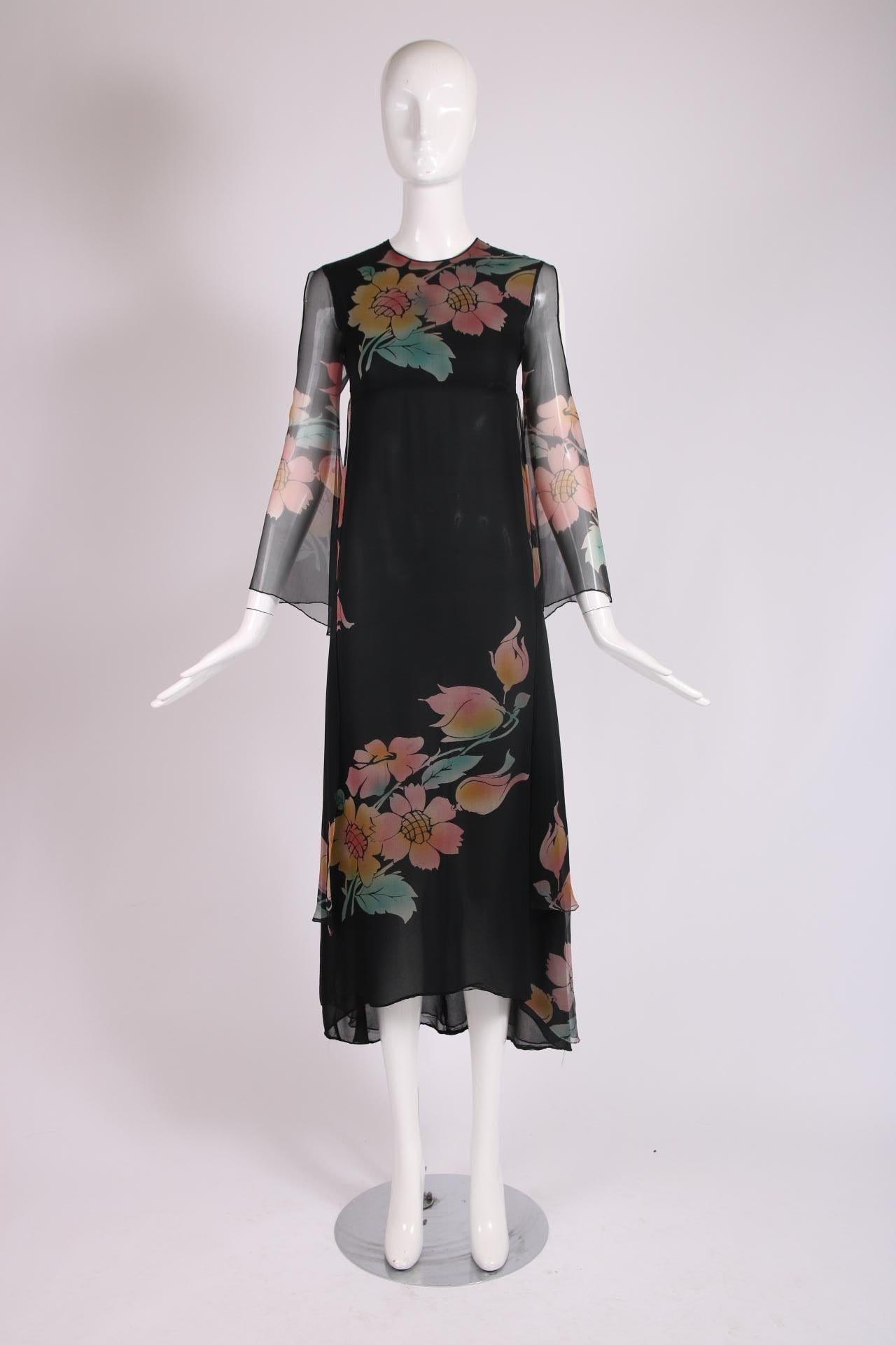 1970's Thea Porter Couture label black multi layered chiffon gown with an empire silhouette, an asymmetric floral print, a high-low hem, floating fabric panels at the back, cutouts at the upper sleeve which tapers out into a mild flute shape at the