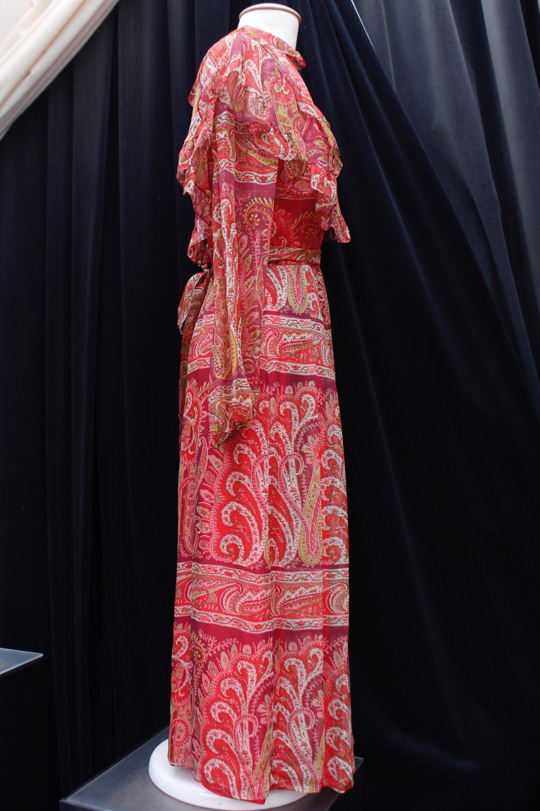 THEA PORTER (Made in France) Beautiful long bohemian style dress composed of silk chiffon printed with a Paisley pattern in red, white and green tones. The long sleeves are tightened at the bottom by elastic. The bust features flounces and the waist