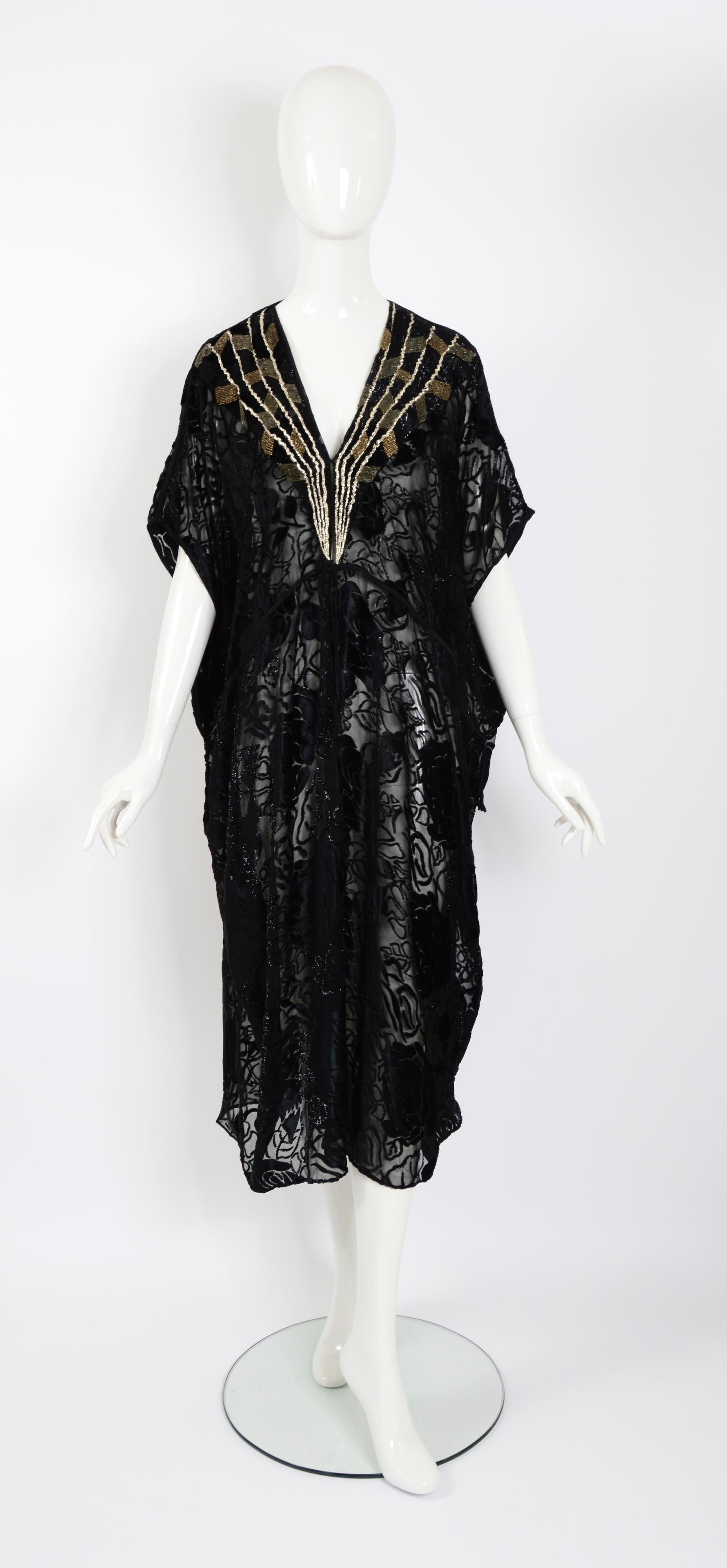 Magnifique caftan Thea Porter Couture. 
Le caftan est principalement composé de velours de soie noir dévoré à motif floral. Des perles dorées et argentées courent horizontalement et en diagonale entre les bandes. La robe, qui ressemble à un caftan,