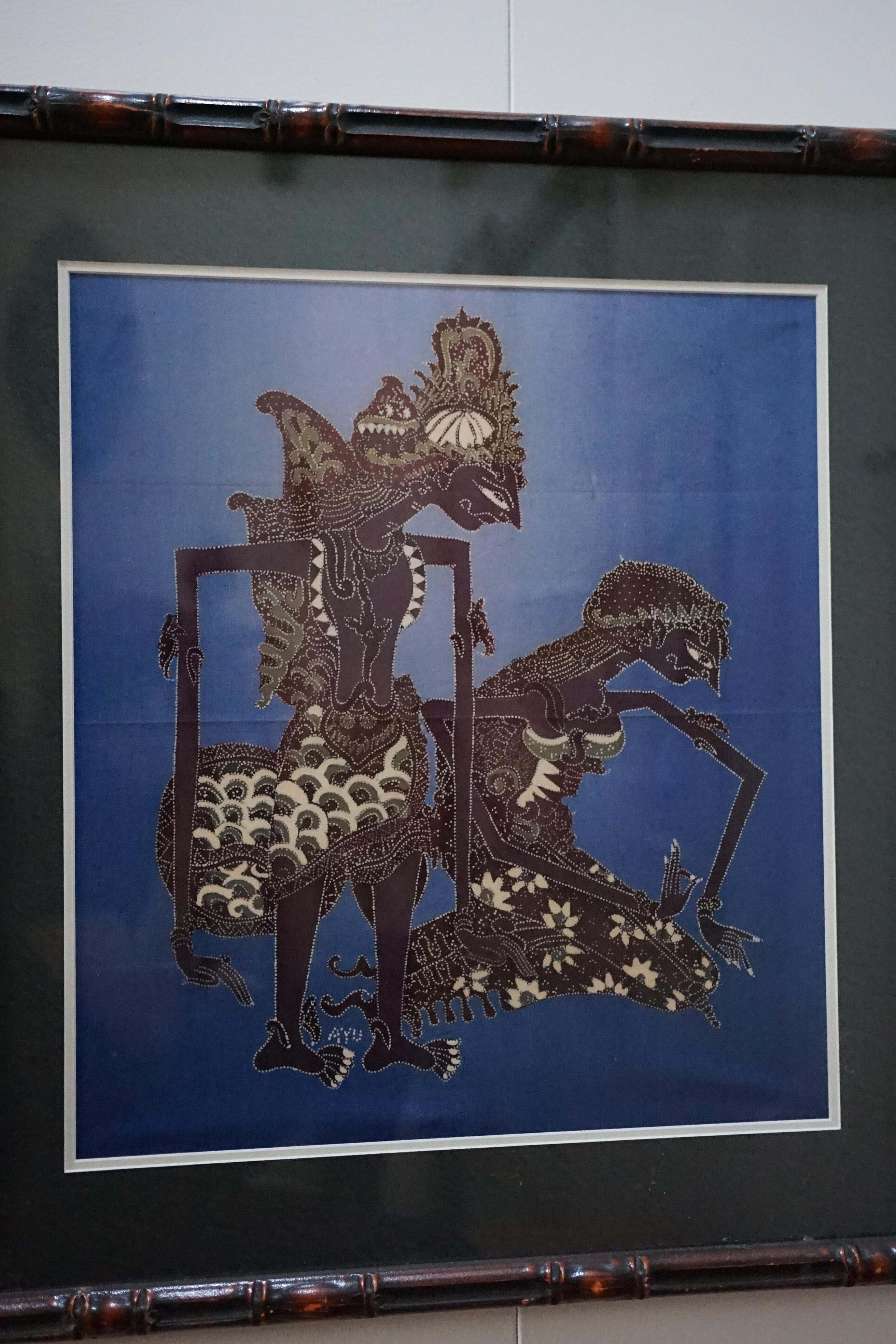 Theater of Shadows
Signed by Ayu, this richly detailed batik painting evokes the ceremonial beauty of Southeast Asia’s Wayang Kulit shadow puppetry. Two stylized figures—one regal and upright, the other kneeling—are rendered in intricate pointillist