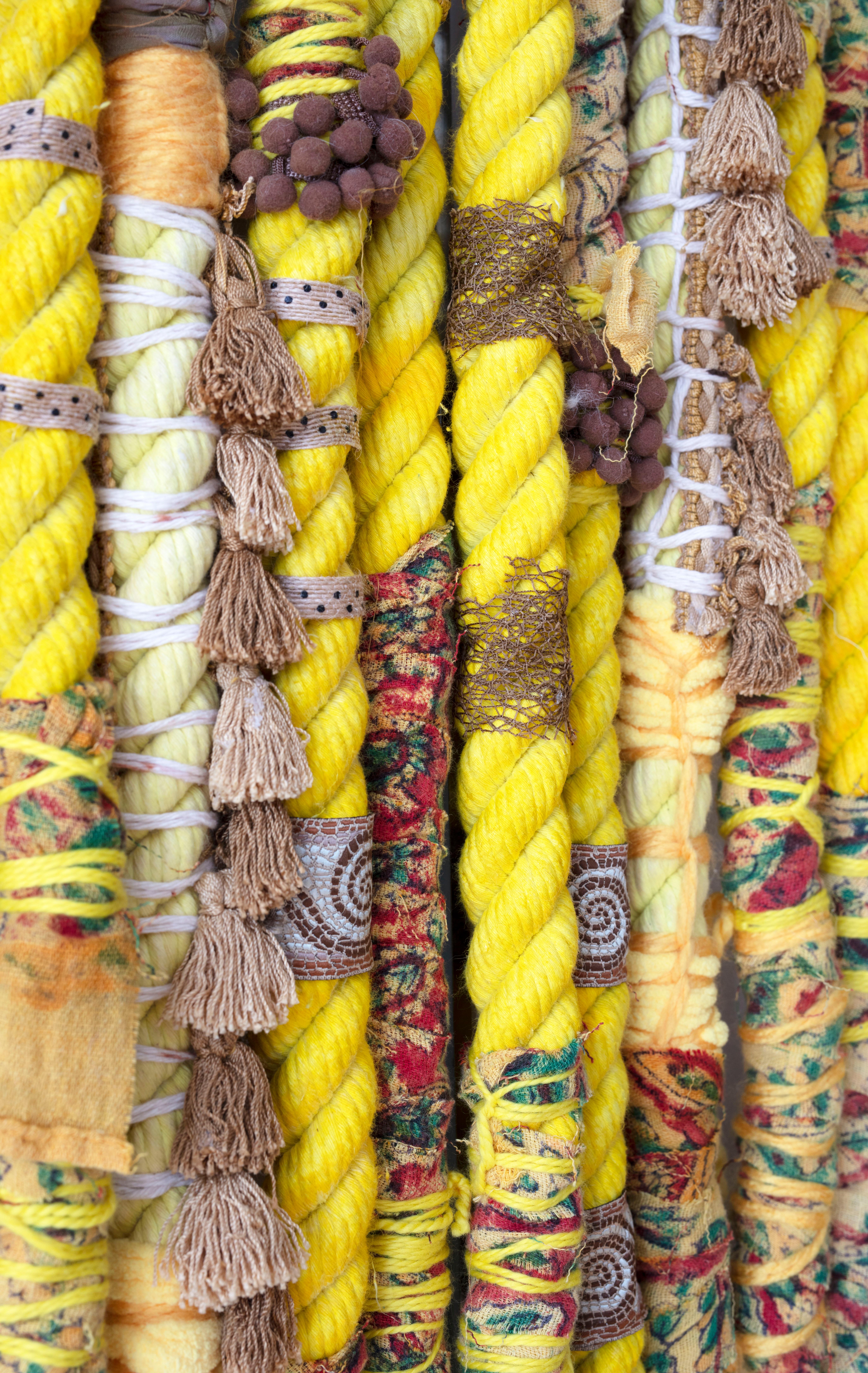 I custom dyed the cotton rope a bright yellow using Jacquard ink, then wrapped the rope with ribbon, pom pom trim, yarn and vintage fabric from a block print tapestry that hung in my college dorm room.

Theda Sandiford, is a self-taught mixed media