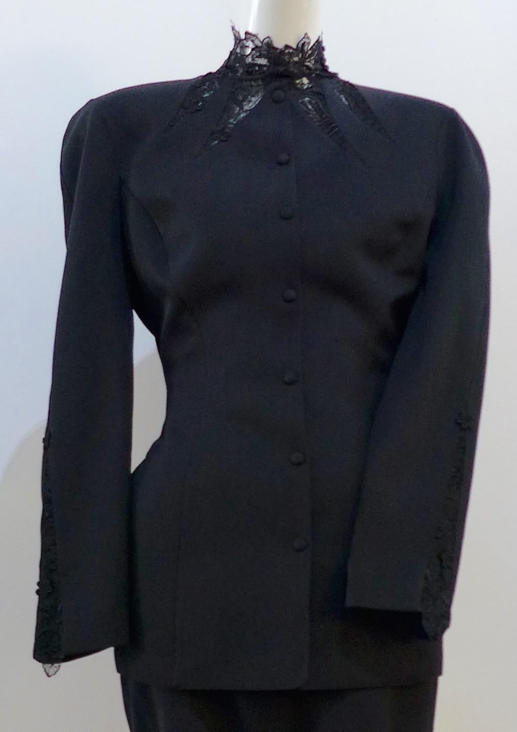 This THIERRY MUGLER skirt suit is composed of a black polyester and lace fabric. Features a classic Mugler silhouette with nipped waist and curved bust-line to neckline design. The jacket has front snap closures, rounded shoulders, and lace panels