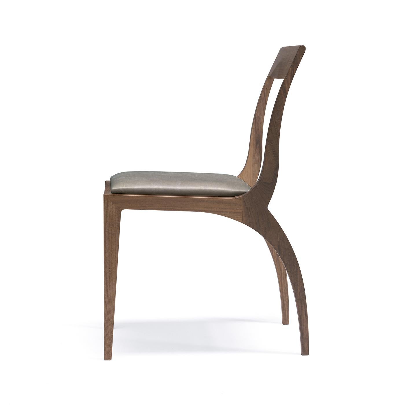 Designed by architect Fabio Rebosio, this chair is a sophisticated accent piece that combines functionality and a highly decorative quality. Its structure in solid Canaletto walnut boasts curved back legs that find a delicate counterpart in the open