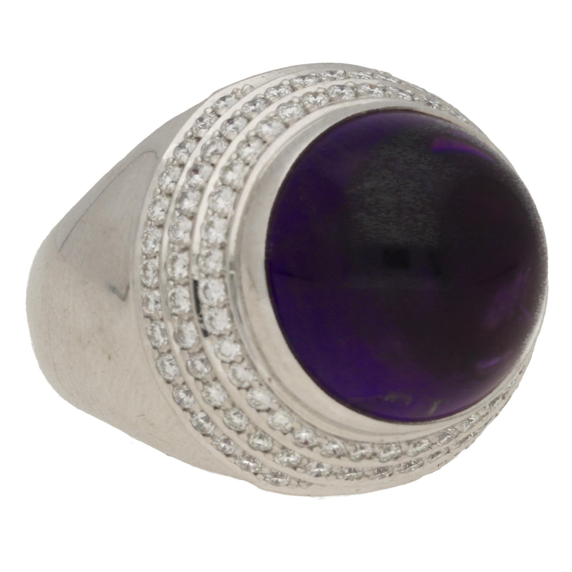 A striking amethyst and diamond cocktail ring set in 18k white gold, signed Theo Fennell.

The piece is predominantly set with a central cabochon amethyst stone which has an approximate carat weight of 12.00 carats. The amethyst is a vibrant purple
