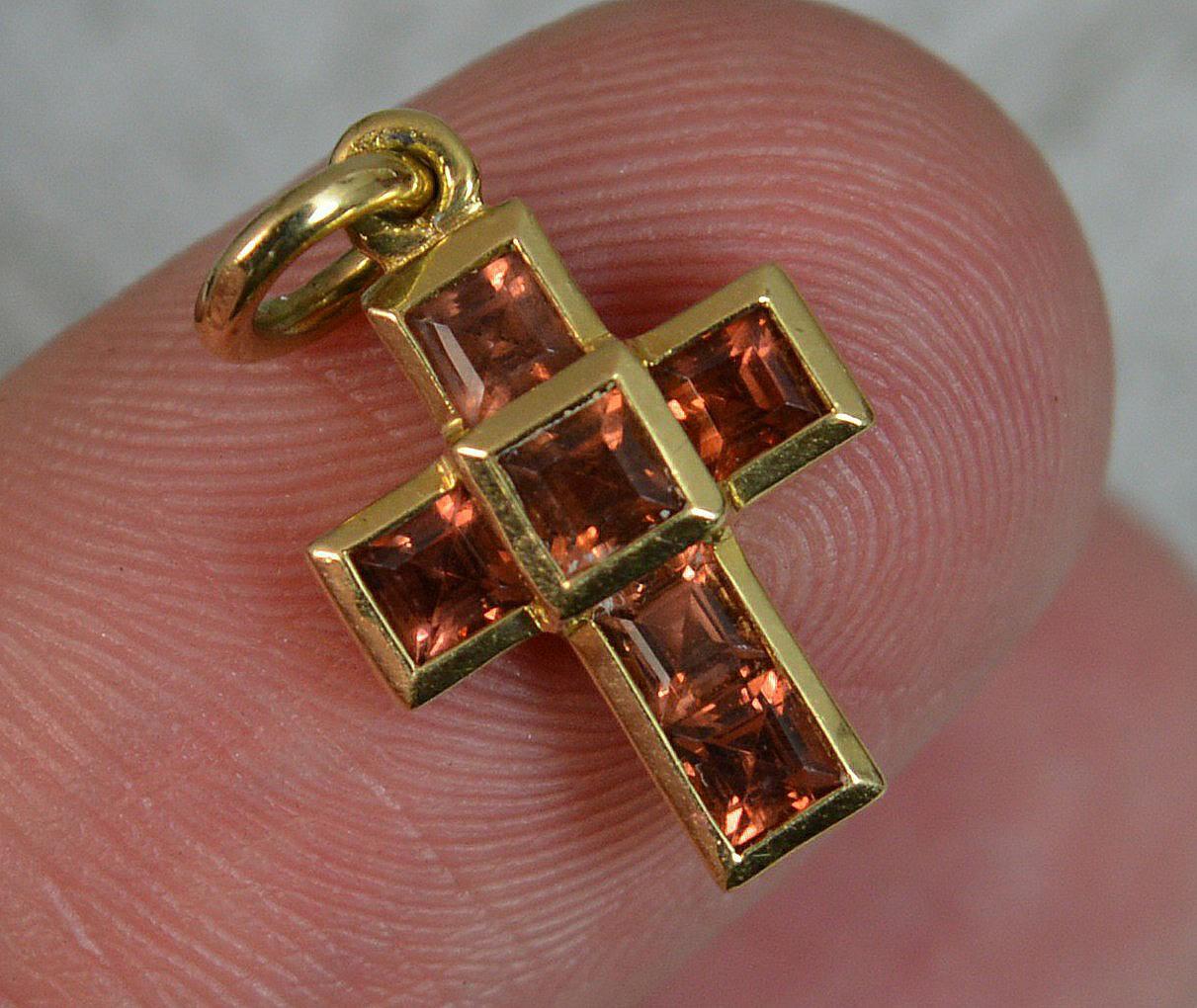 A beautiful THEO FENNELL designer cross charm pendant.
Solid 18 carat yellow gold example.
Set with six princess cut garnet stones.

CONDITION ; Excellent. Well set stones. No issues throughout. Please view photographs.
WEIGHT ; 1.5 grams
SIZE ;