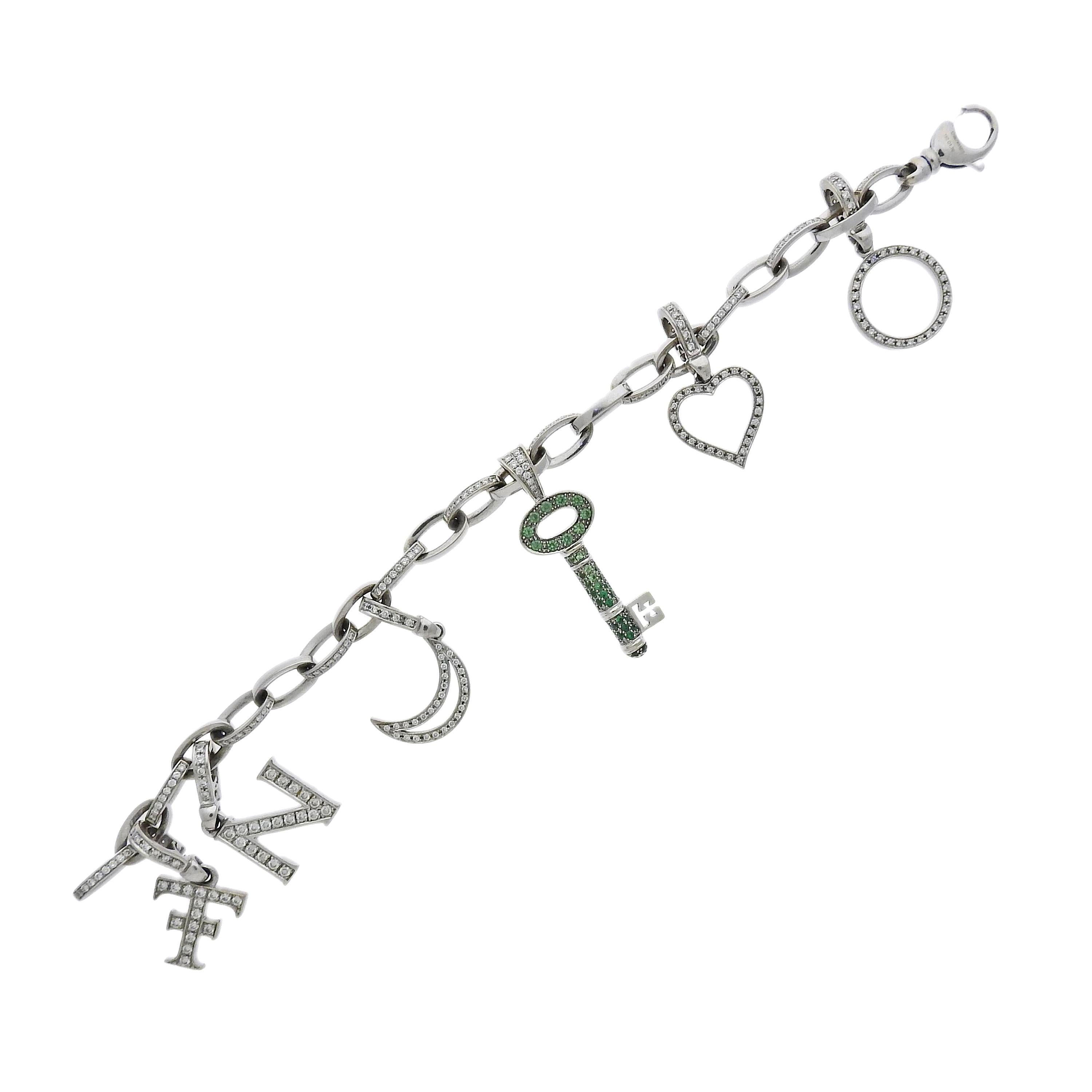 Theo Fennell white gold link charm bracelet features 1.70ctw in SI/GH diamonds, tsavorite. All charms are detachable. Bracelet measures 7 3/4