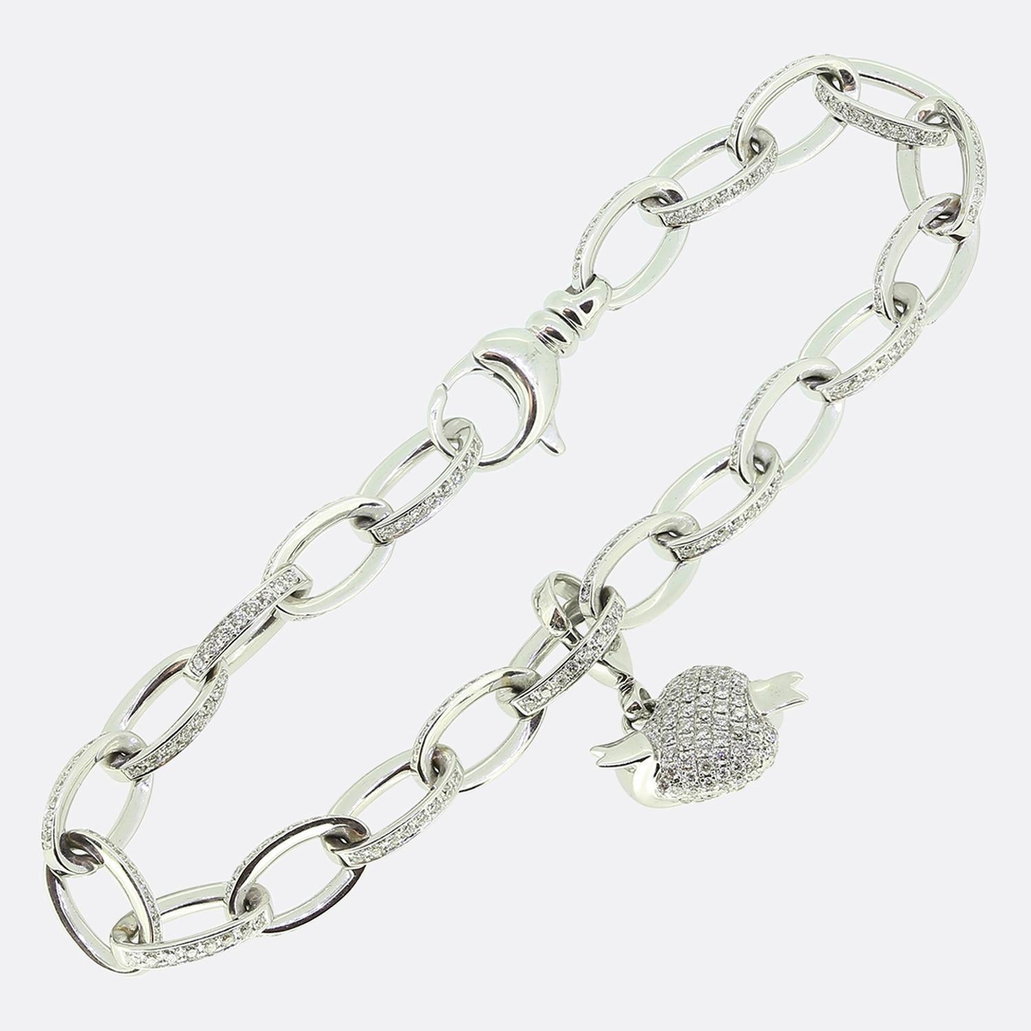 Voici un fabuleux bracelet à breloques de Theo Fennell. Réalisée en or blanc 18 ct, cette pièce présente une série de maillons ovales emboîtés, chacun orné de diamants ronds de taille brillant. La breloque focale a été façonnée selon l'un des motifs