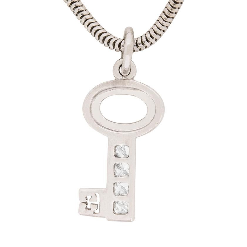 This second-hand Theo Fennell key pendant is made in 18 carat white gold and features three princess cut diamonds, channel set in the key. The diamonds have a combined weight of 0.20 carat and are F in colour, VS in clarity. The key pendant is an