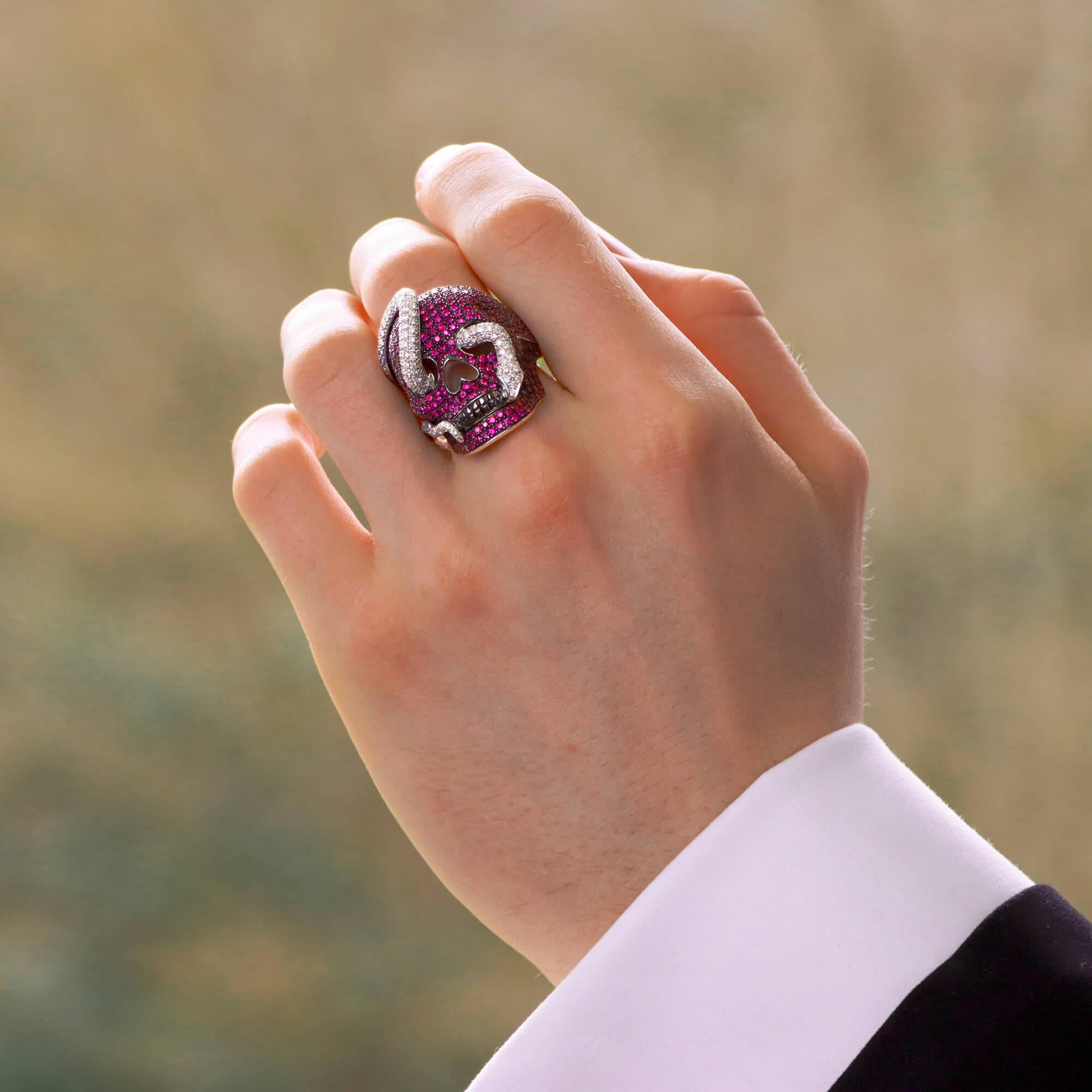 Ein sehr auffälliger Ring von Theo Fennell mit einem Rubin und einem Diamanten als Totenkopf und Schlange, gefasst in 18 Karat Weißgold. 

Der Ring besteht zunächst aus einem rhodinierten Totenkopf, der durchgehend mit schönen Rubinen im Rundschliff