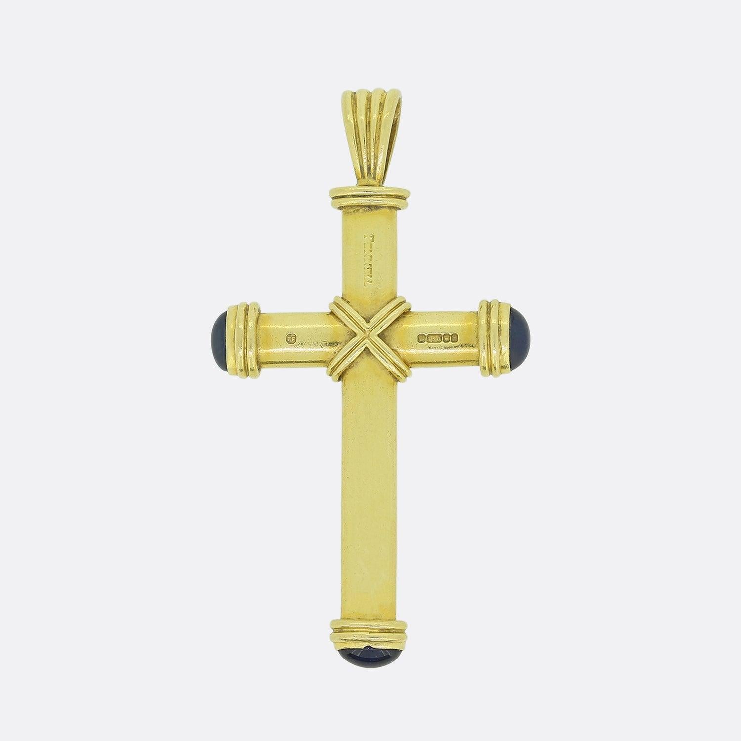 This is a wonderful cross pendant from the world renowned jewellery designer, Theo Fennell. The pendant has been crafted in 18ct yellow gold and has been rubover set with three cabochon blue sapphires on each side of the cross and in the centre.