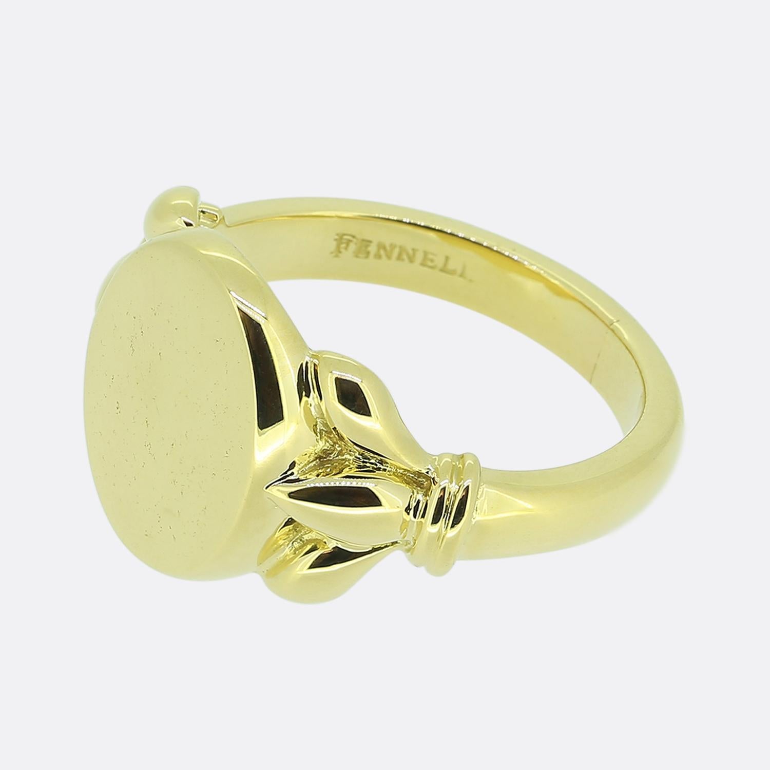 Here we have a bold signet ring from renowned British jewellery designer, Theo Fennell. Crafted from lustrous 18ct yellow gold, this piece features a smooth, oval shaped face. The design is accentuated by intricate detailing on the shoulders, adding